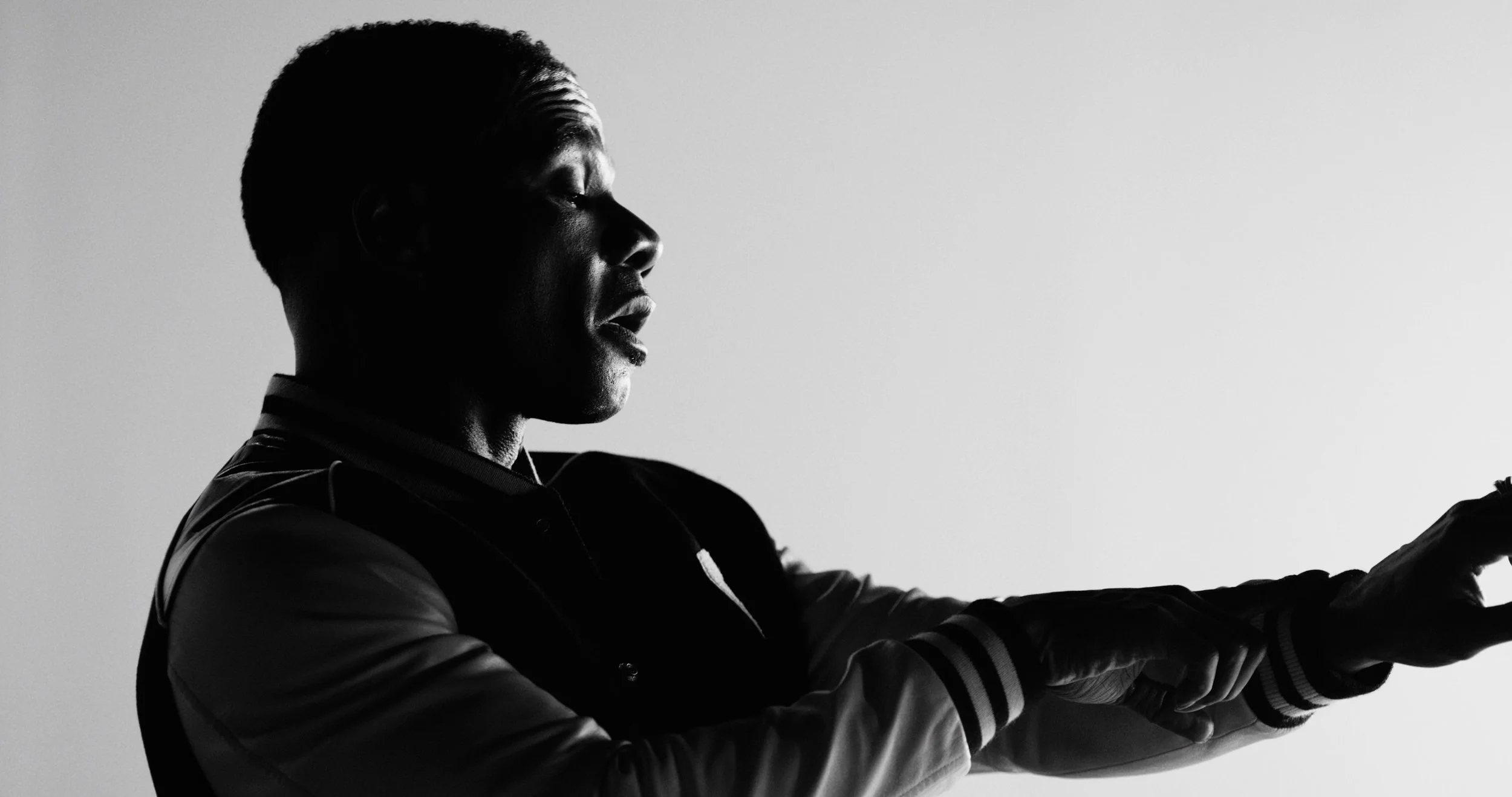 Silhouette of a man with closed eyes looking down, with arms extended forward, black and white photo