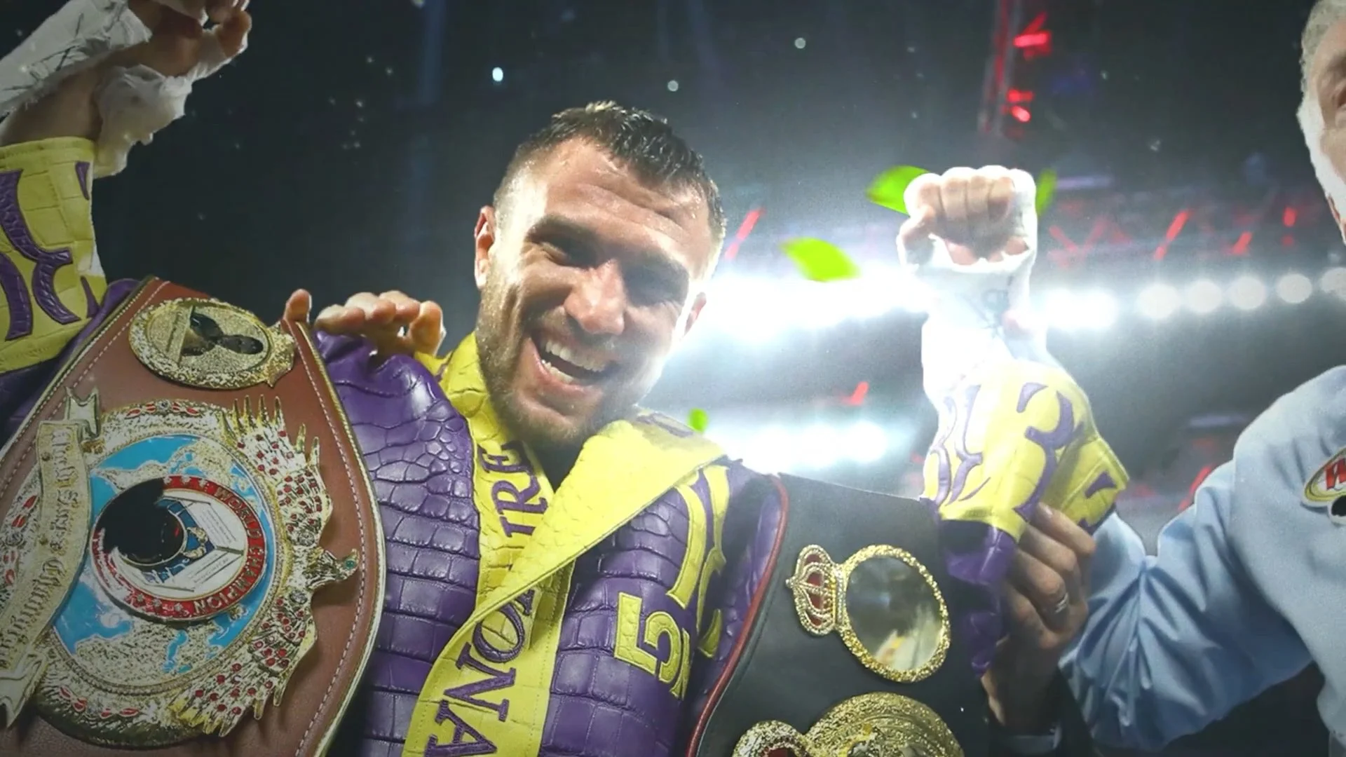 A victorious male boxer wearing championship belts and purple and yellow boxing gear, smiling and celebrating in a brightly lit arena.