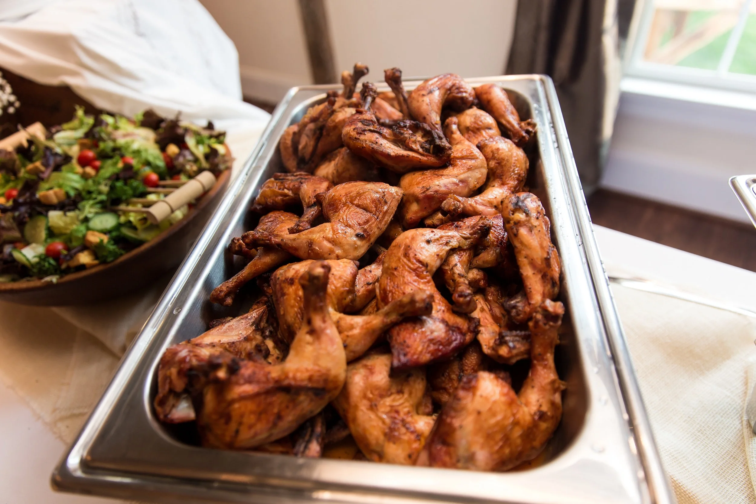 Tray of grilled chicken pieces at a buffet.
