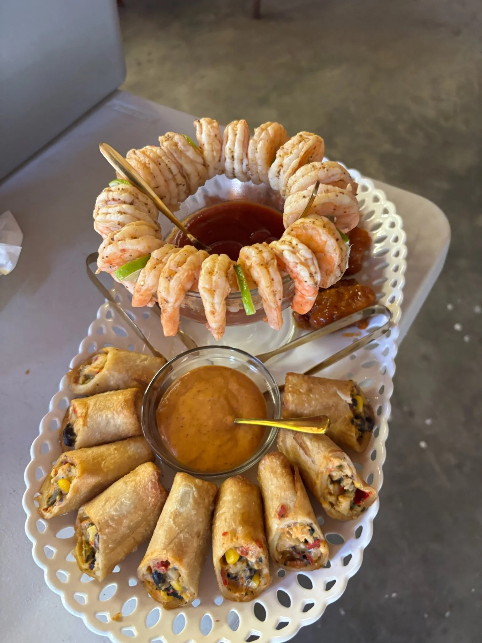 Plate of shrimp with dipping sauce, spring rolls, and a bowl of dipping sauce.