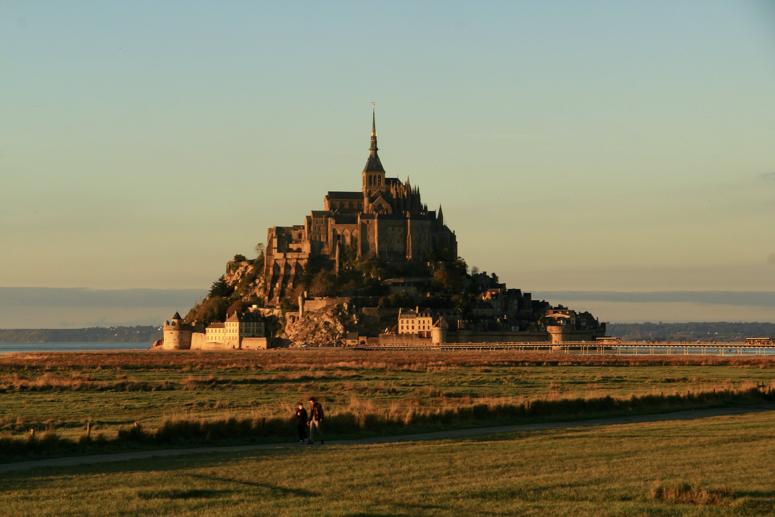 Mont Saint-Michel, a historic island commune with a medieval monastery, rising above the surrounding landscape during sunset or sunrise.