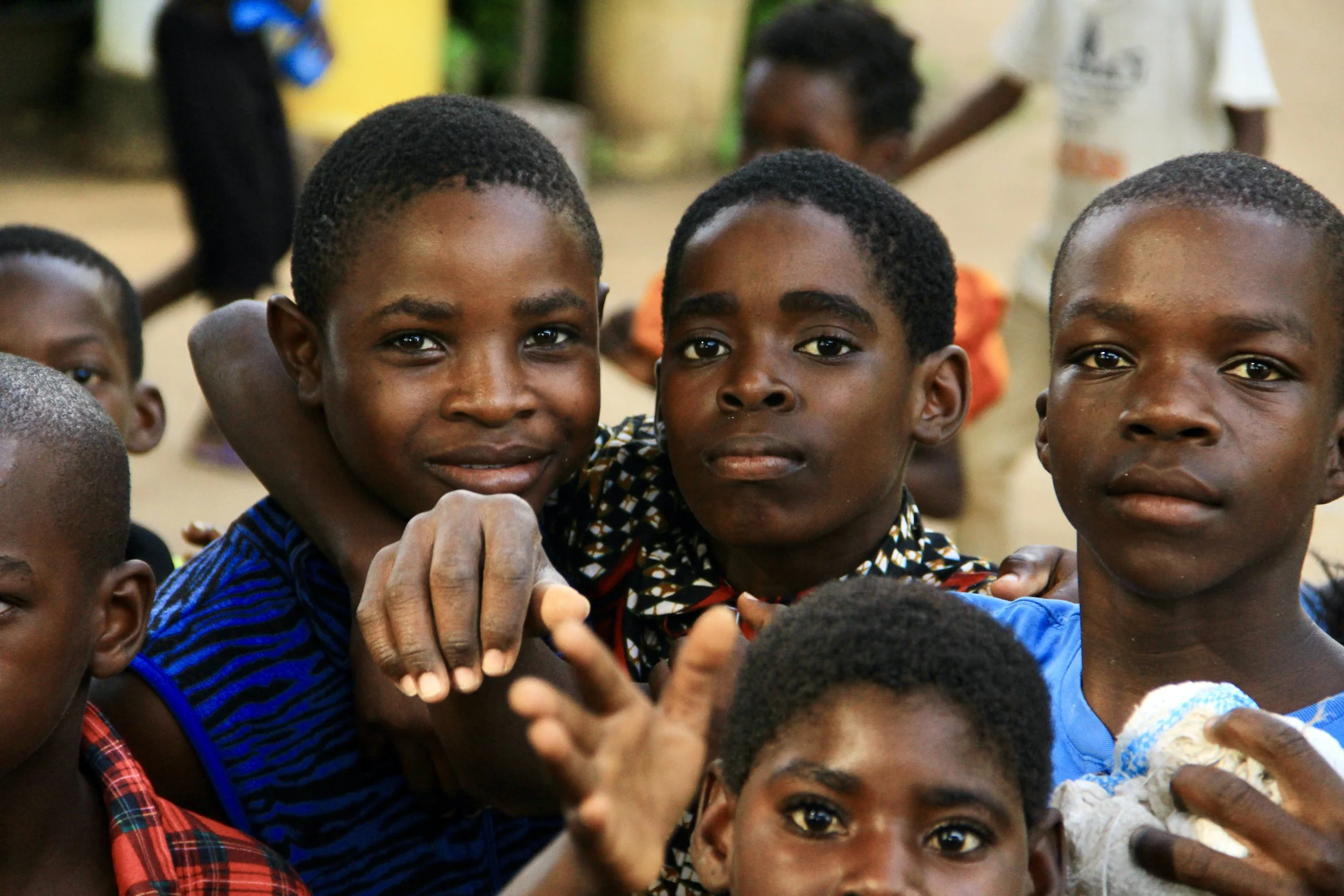 Group of young African children outdoors, some smiling and looking at the camera.