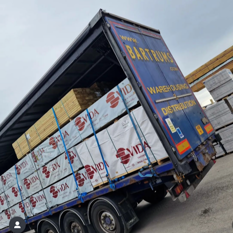 Blue delivery truck with the text 'BATRUMS Warehouseing Distribution' parked at a storage or distribution facility.