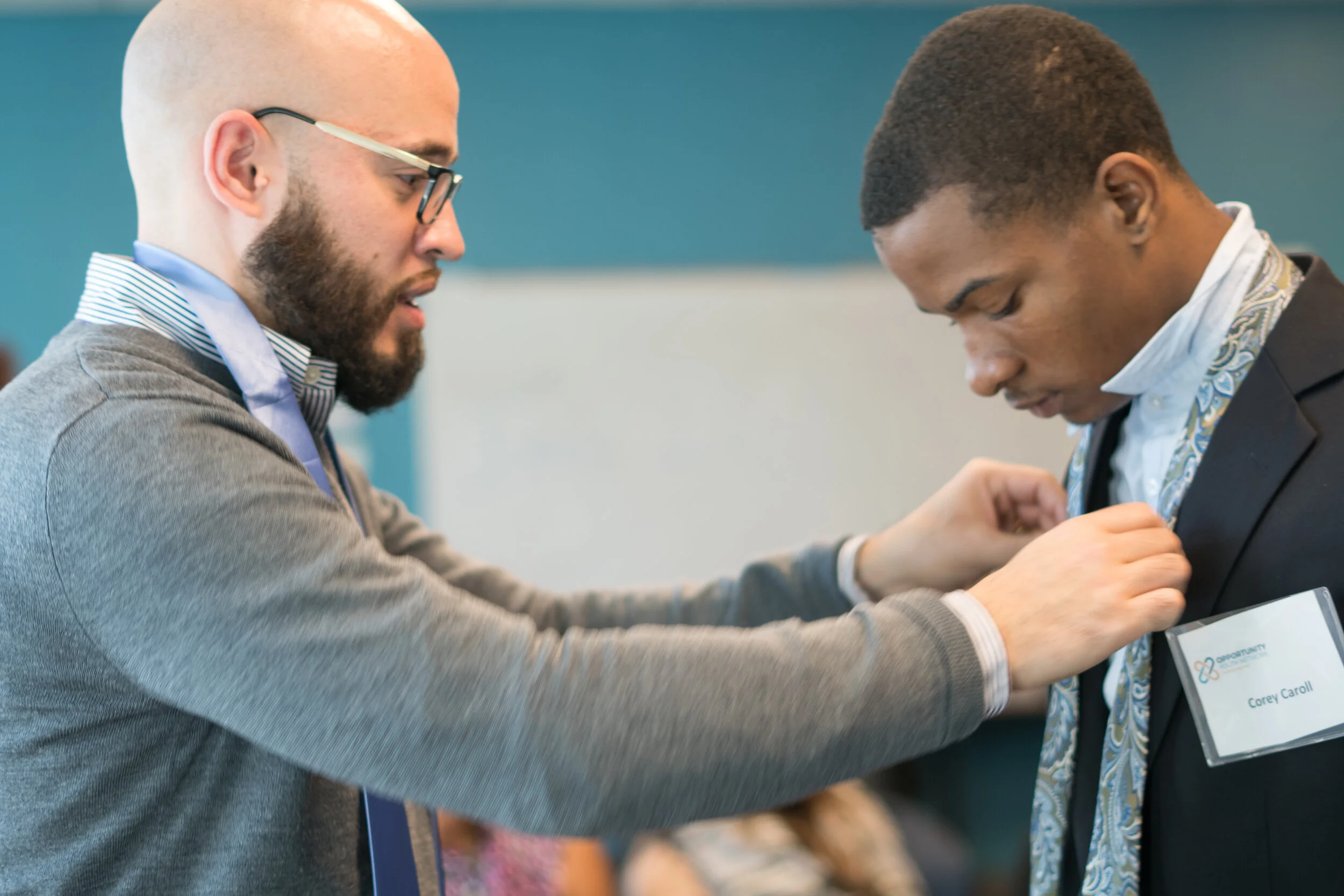 Mark Comesañas helps tie a YouthBuild alum’s tie.