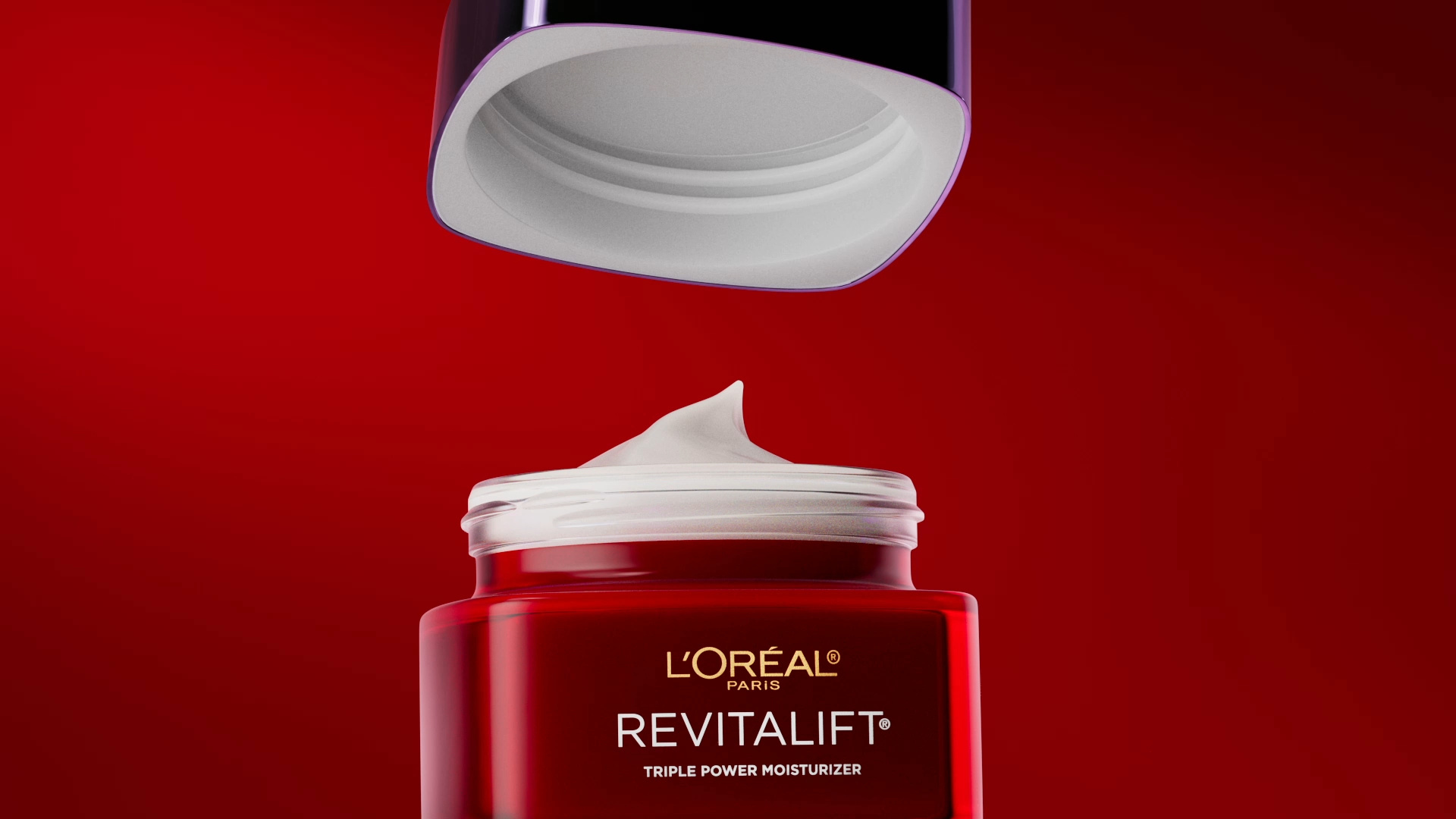 A jar of L'Oreal Paris Revitalift triple power moisturizer with the lid being removed, against a red background.