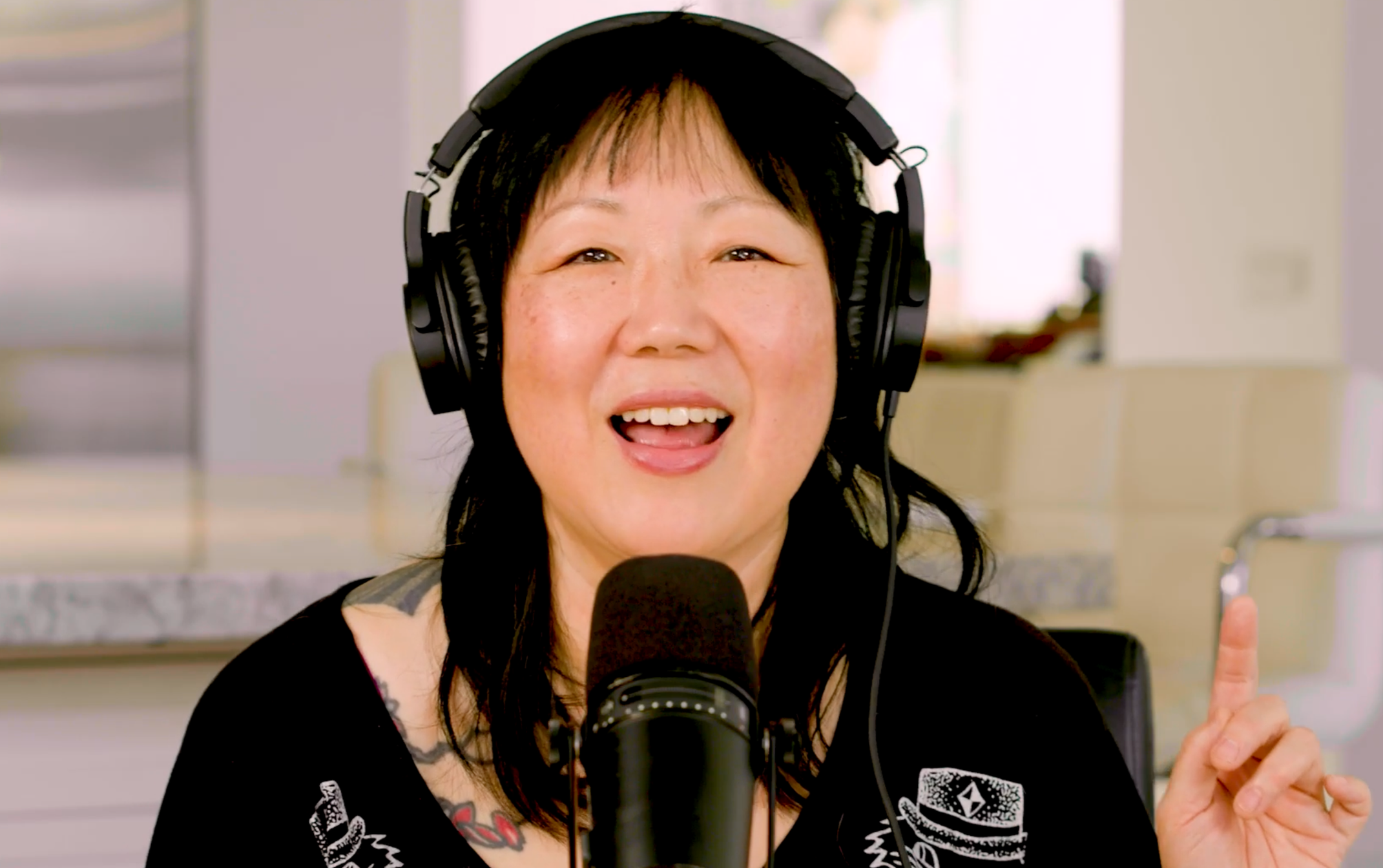 A woman speaking into a microphone, wearing headphones, and gesturing with her finger.