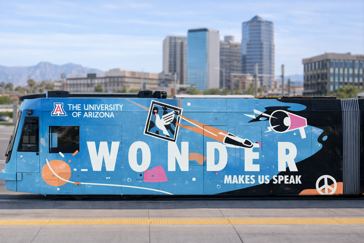 Bus with a colorful mural including university branding from the University of Arizona, the word "Wonder," and images of a dove, peace symbol, and artistic splashes, set against an urban cityscape background.