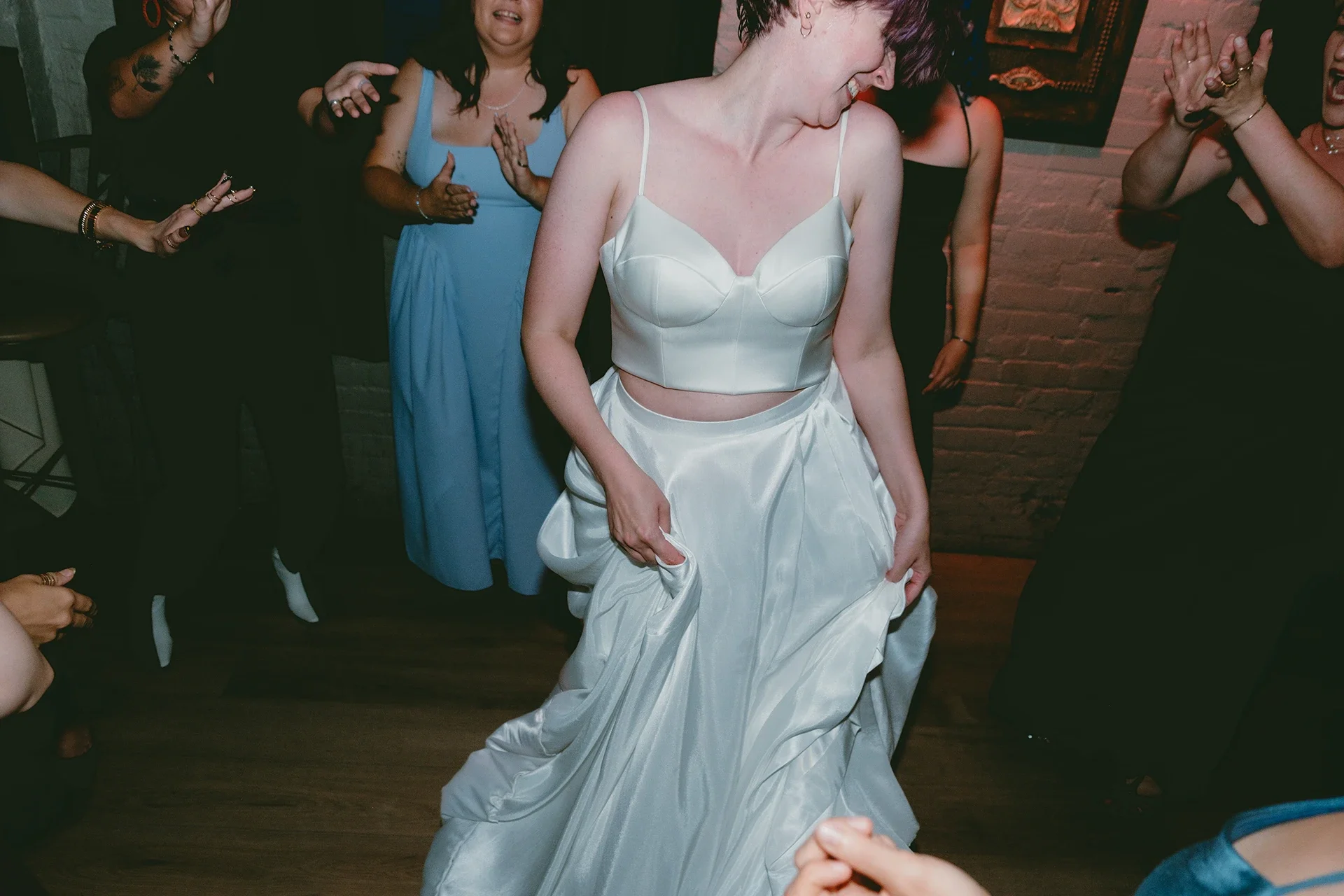 Woman in a white wedding dress dancing at a celebration with friends