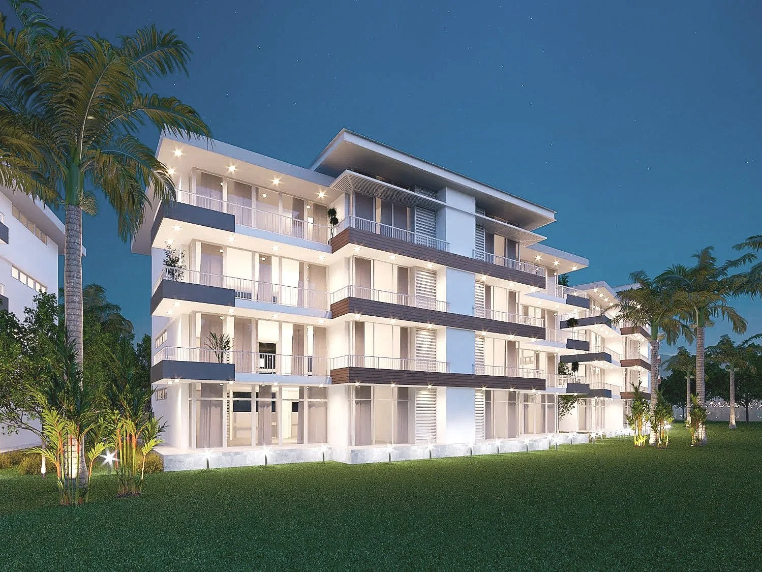 Edificio moderno de varias plantas con balcones y ventanas amplias, rodeado de palmeras y césped, iluminado durante la noche bajo un cielo estrellado.