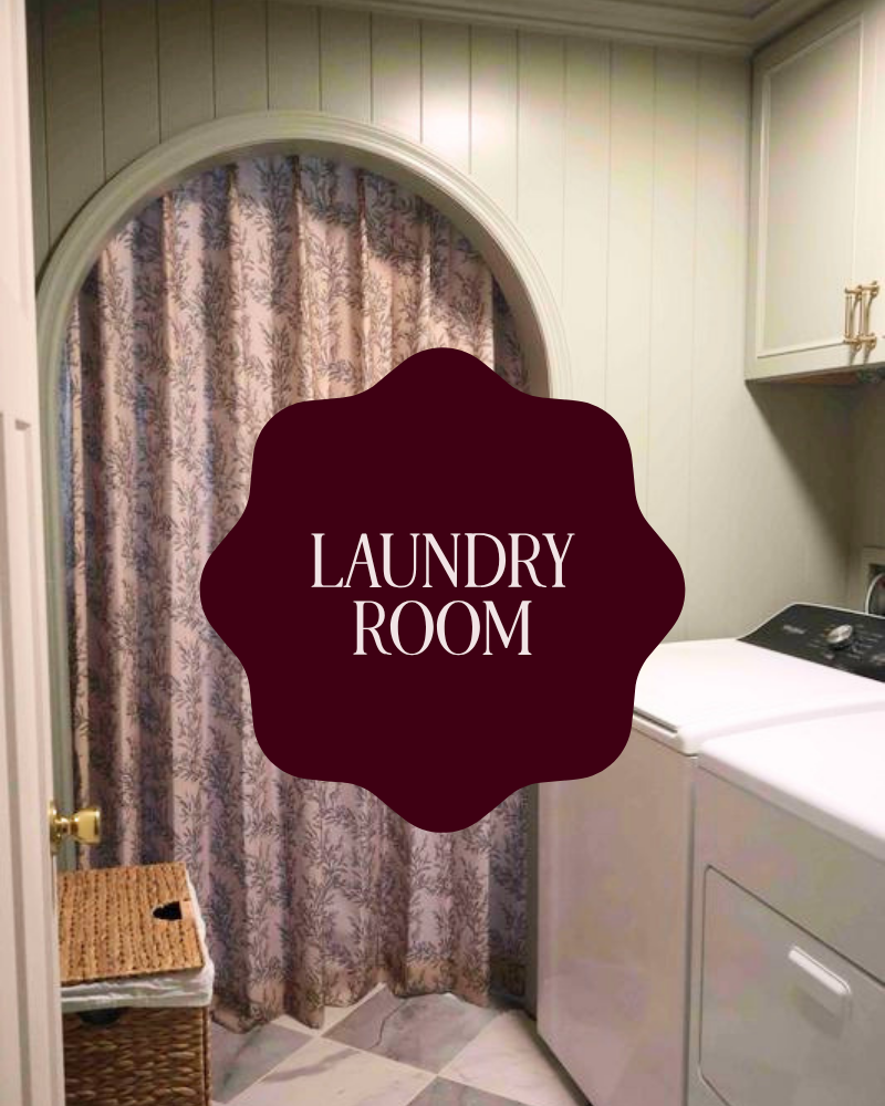 A laundry room with patterned curtains, a wicker laundry basket, and a white washing machine against pale green paneled walls.