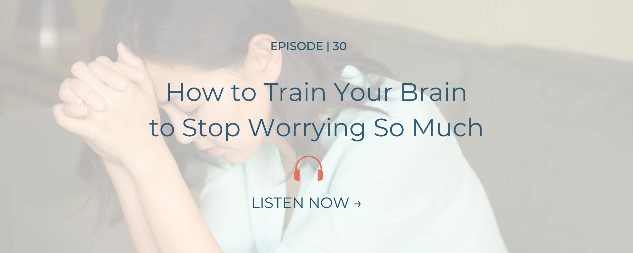 Middle age asian woman sitting down with hands together pressed against her forehead.