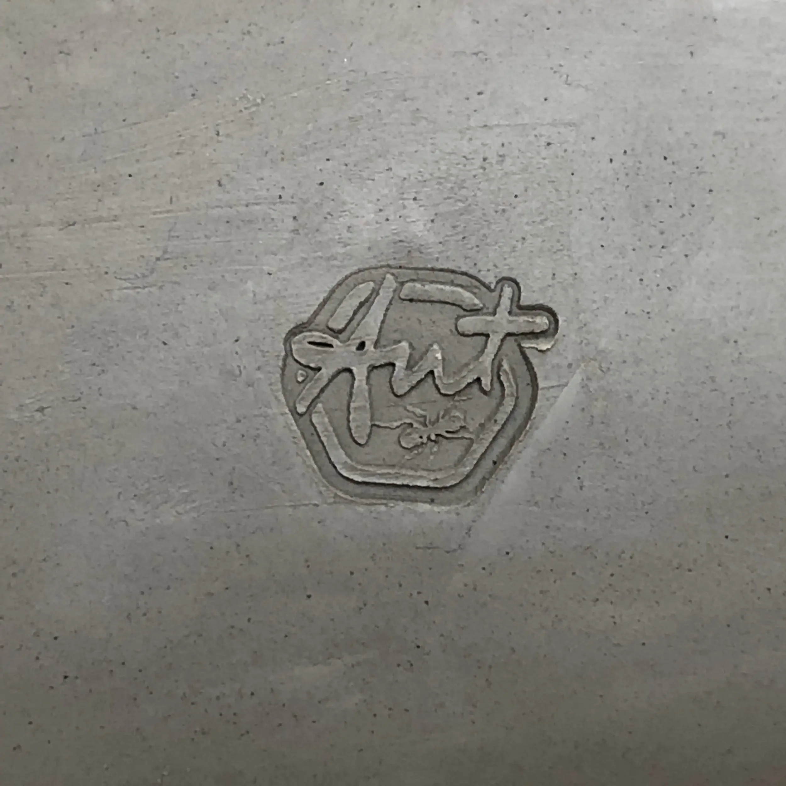 Close-up of a clay surface with a stamped logo that says 'Ant' inside a hexagon.