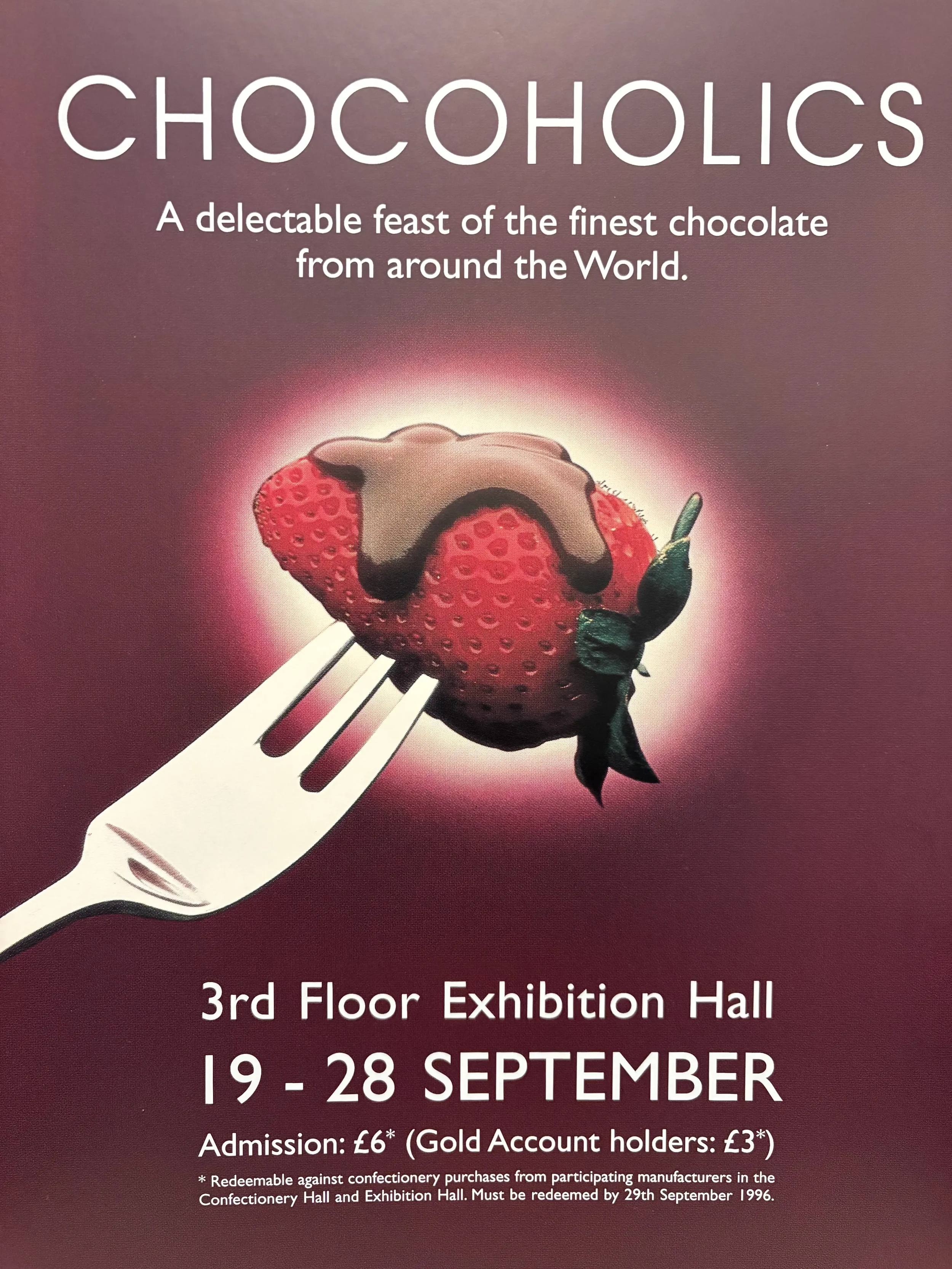 A poster advertising a chocolate exhibition titled 'Chocoholics' with an image of a strawberry topped with chocolate on a fork, set against a pink background.