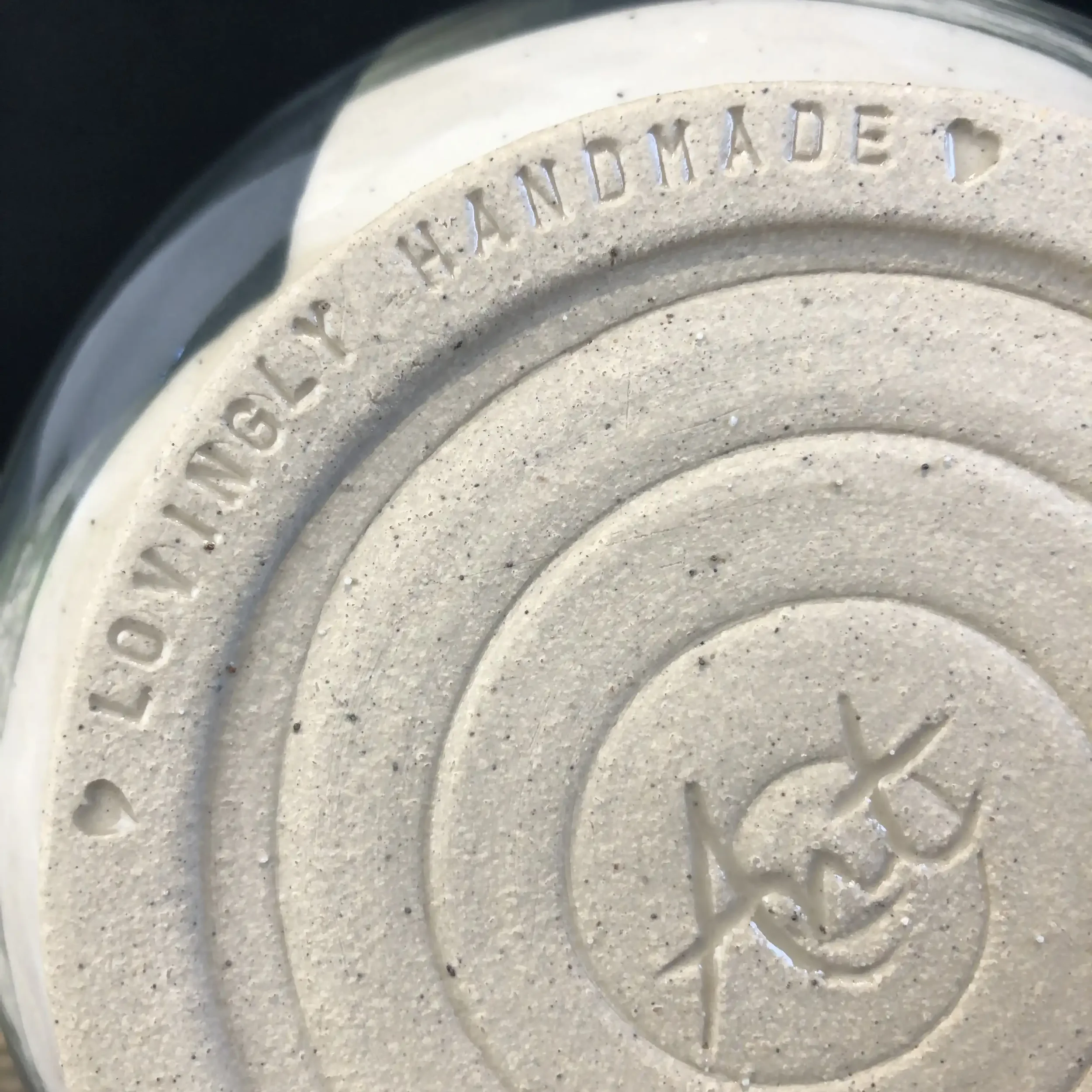 Close-up of the bottom of a ceramic bowl showing embossed text which reads 'LOVINGLY HANDMADE'.