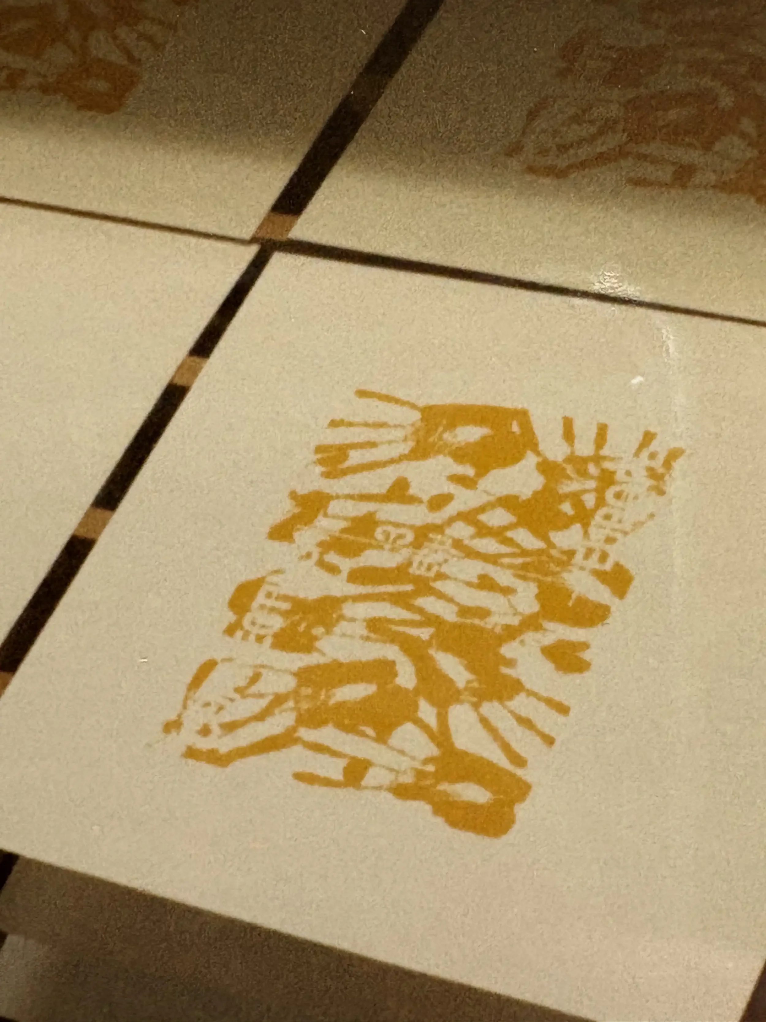 Silk screen printed pages drying on a rack. The print is yellow handprints making the first layer of a design.