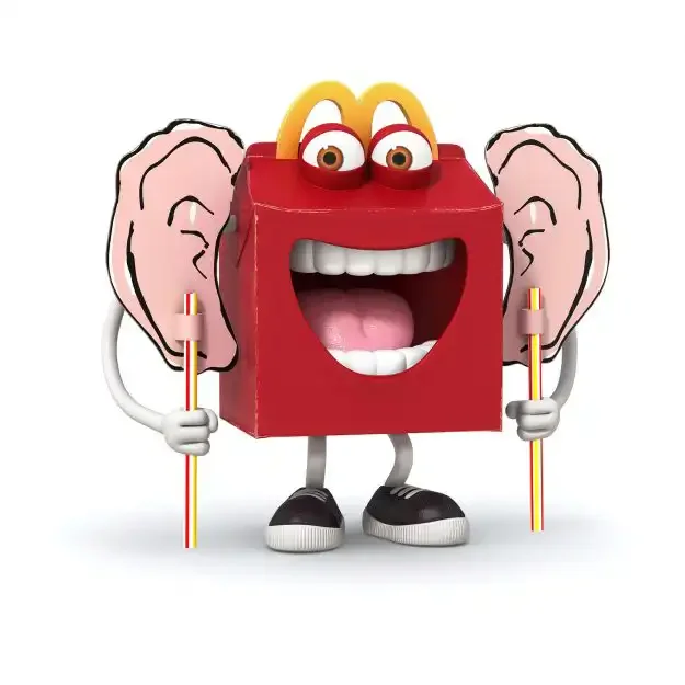 Animated McDonald's Happy Meal box character with human-like eyes, big smile, pink ears, and holding two straws with cut-out cardboard Roald Dahl BFG ears.