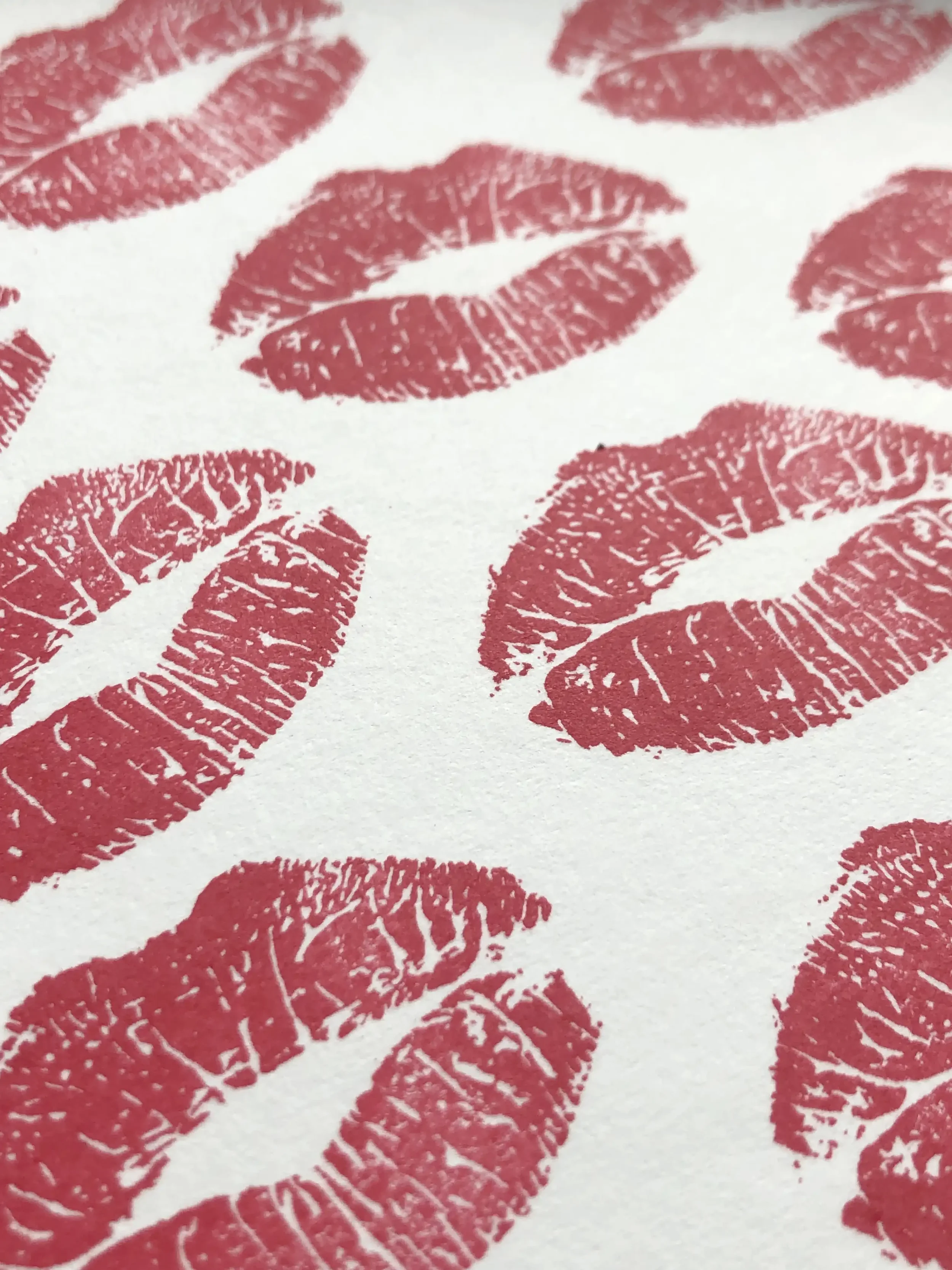 Multiple red lipstick kiss stamped marks on white paper.