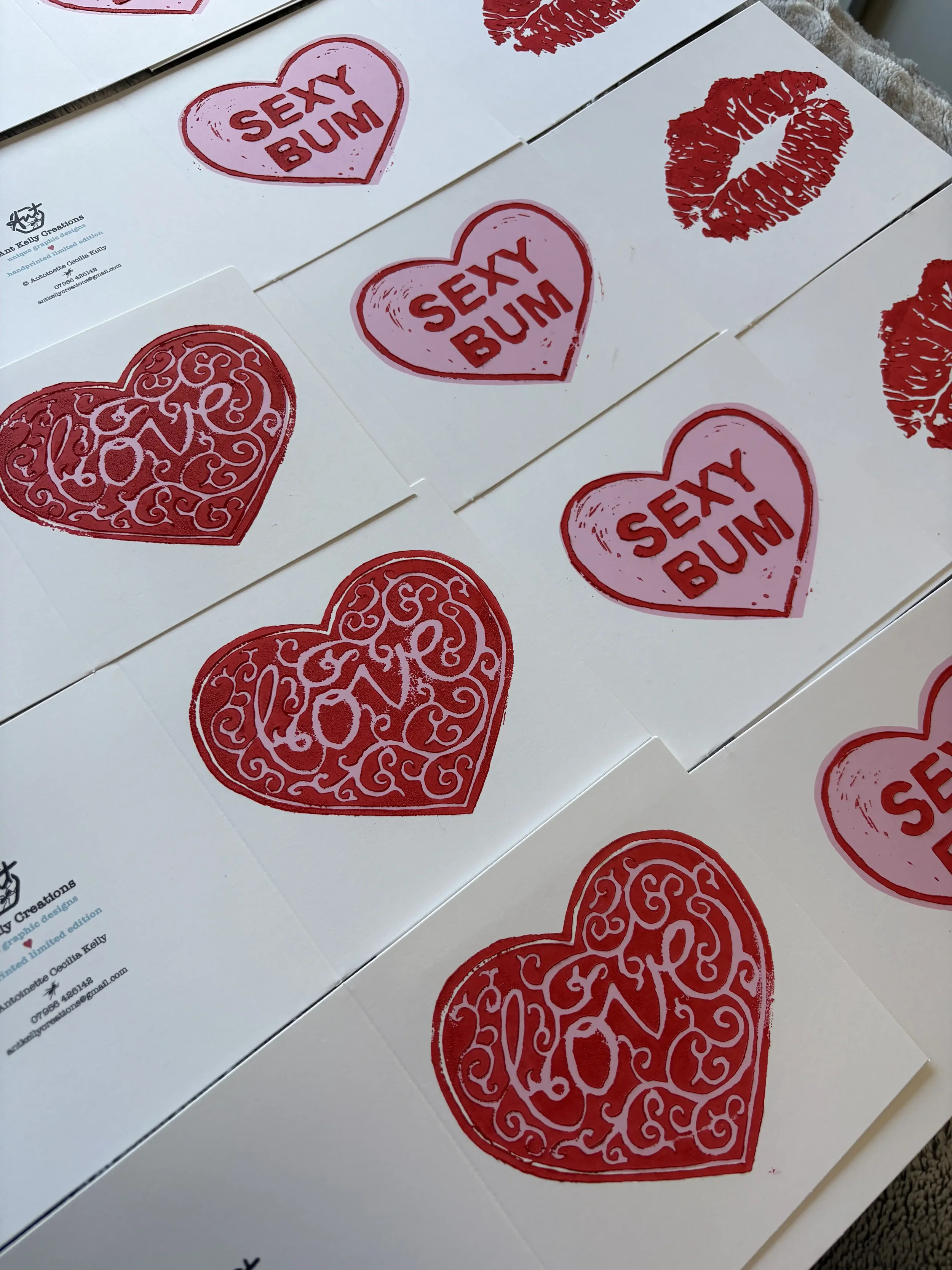 Printed cards with red and pink heart-shaped designs, some with the words 'SEXY BUM' and others with decorative red hearts and kiss marks.