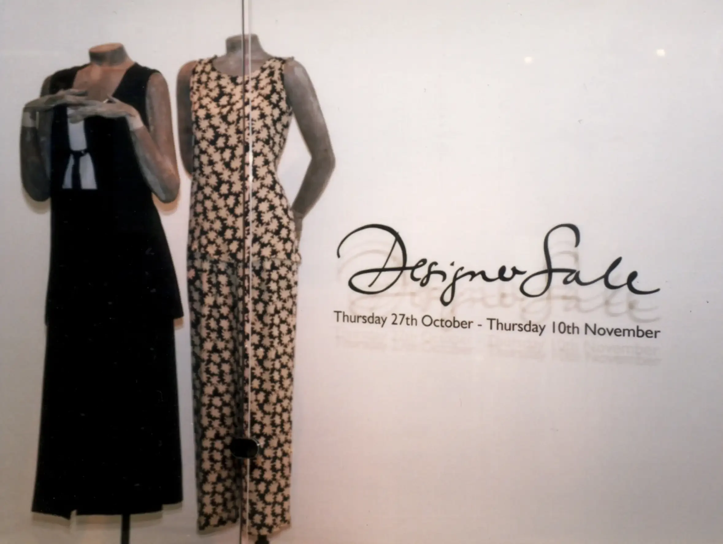 Display of two vintage dresses on mannequins in a fashion sale poster with the text "Designer Sale" and dates from October 27th to November 10th.