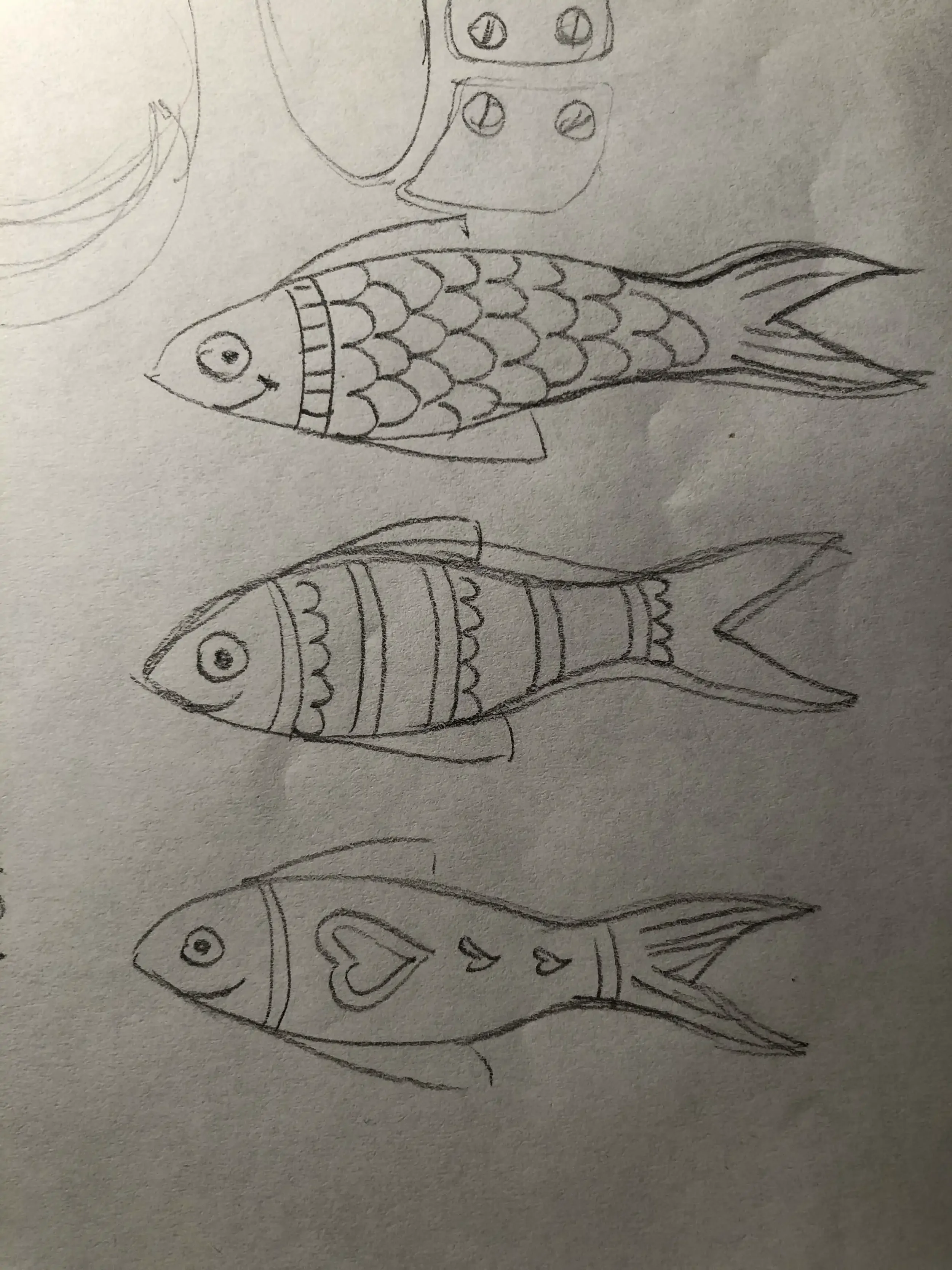 Hand-drawn sketch of three fish with detailed scales and fins, each with expressive eyes, on a piece of paper.