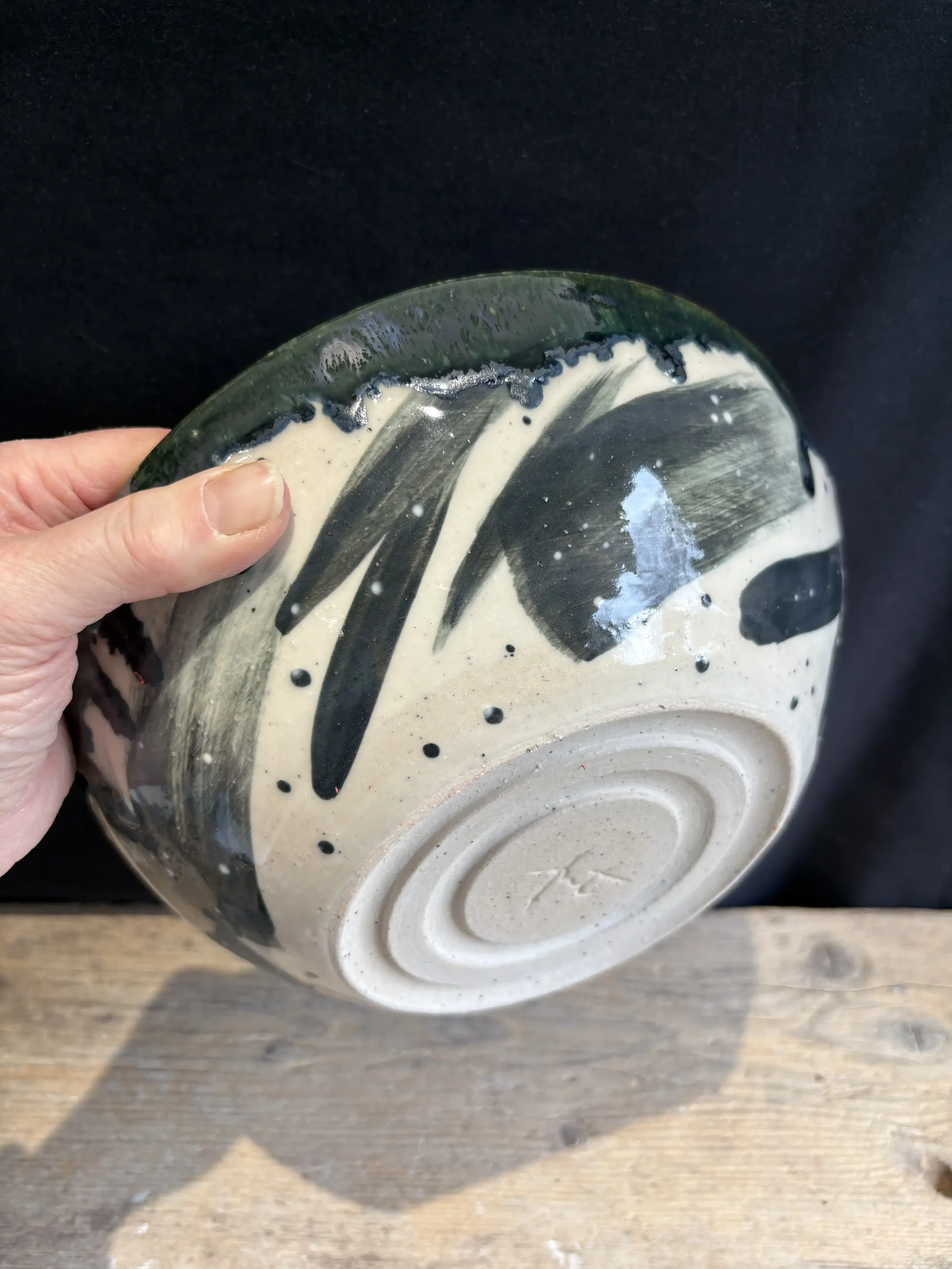 A ceramic bowl with abstract black and white brush stroke design, held by a person's left hand.