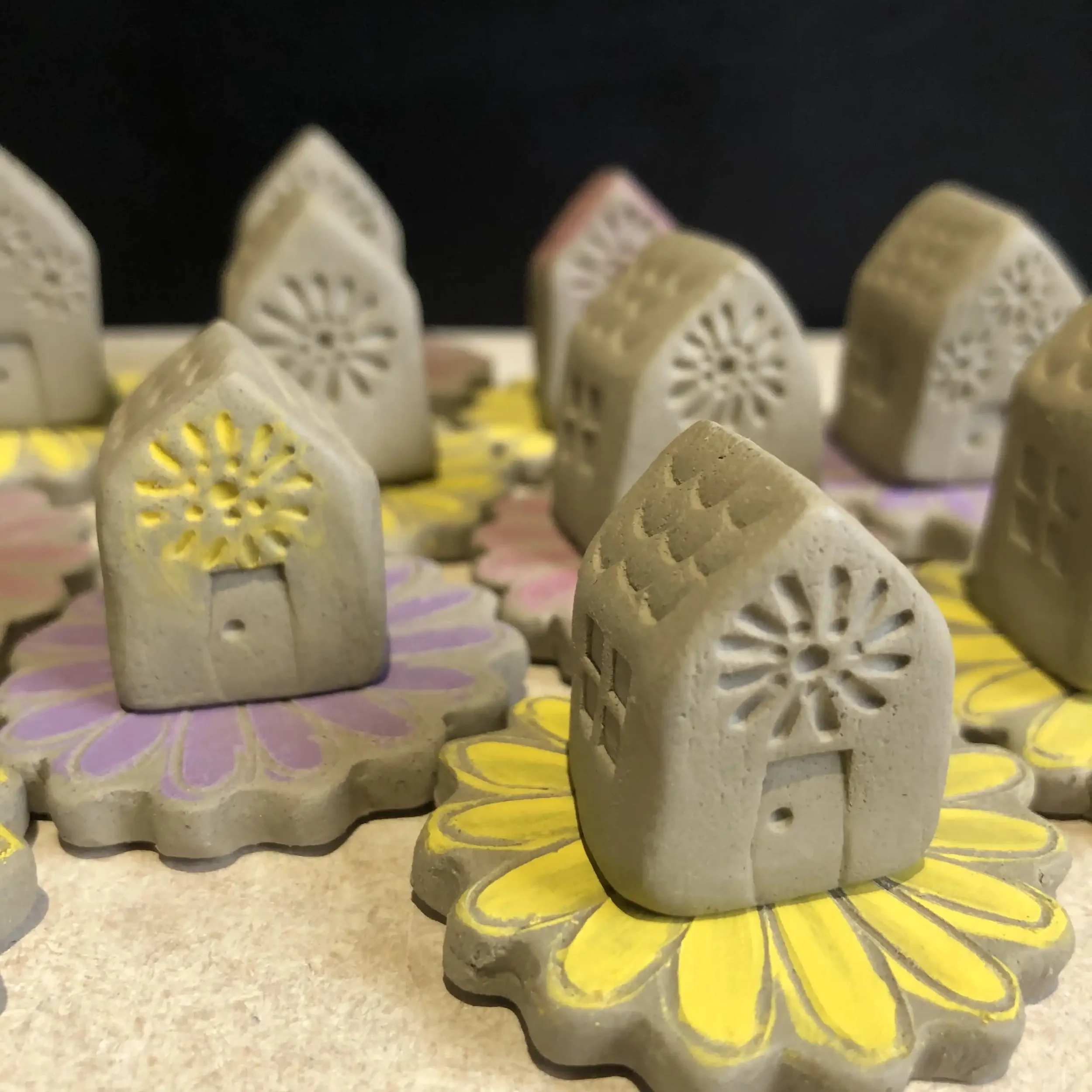 Teeny unfired clay 'flower houses', placed on colourful flower-shaped bases.