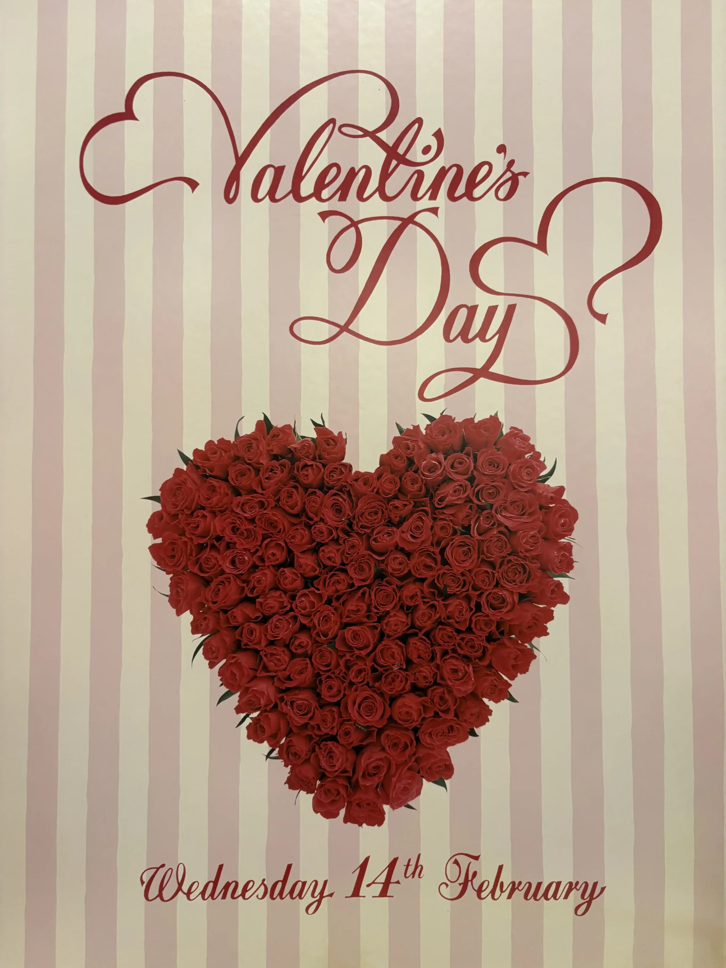 Valentine's Day event poster with a large heart made of red roses on a pink and white striped background and text reading 'Valentine's Day' and 'Wednesday 14th February'.