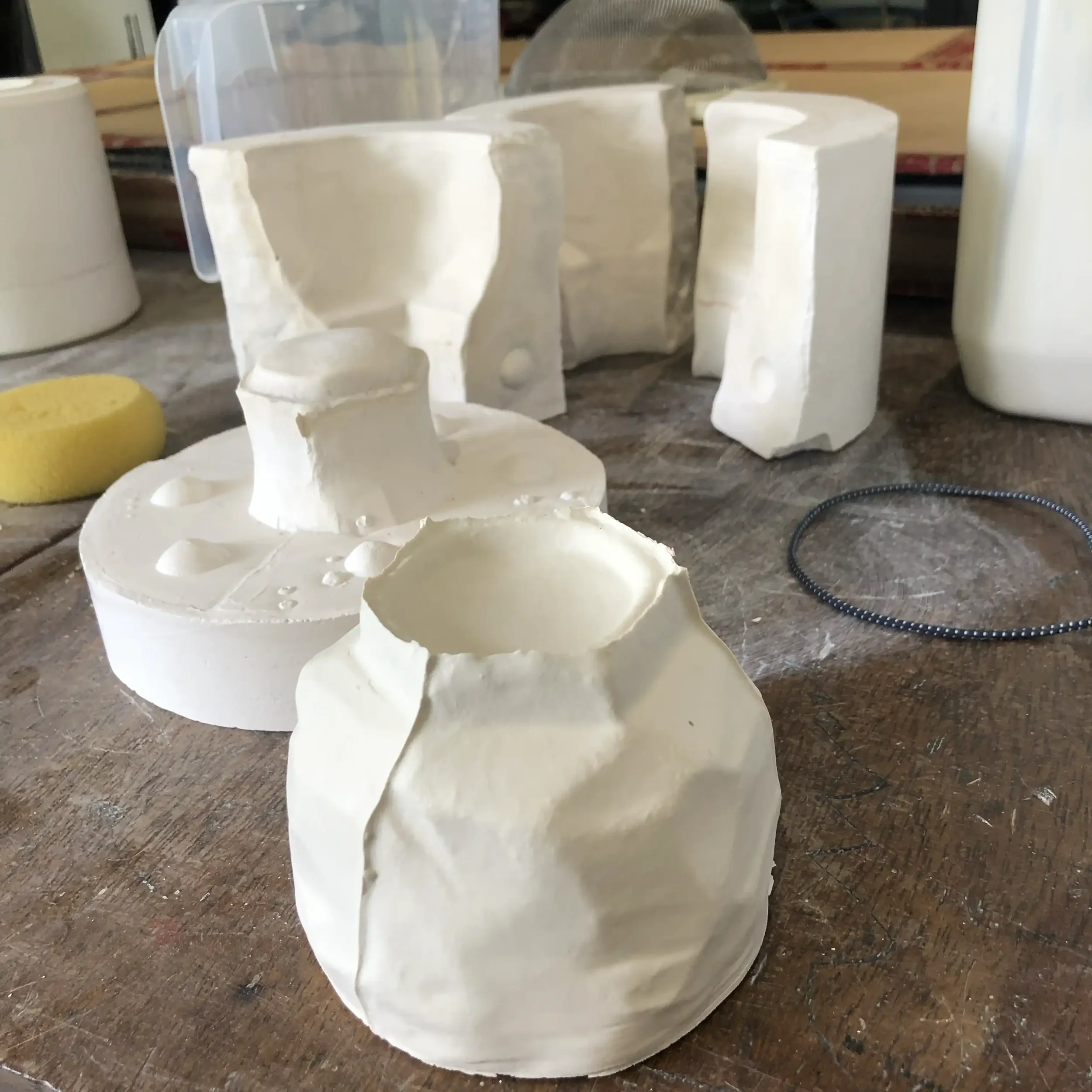 A freshly cast porcelain cup and the mould that it was made from sitting on a wooden workbench.