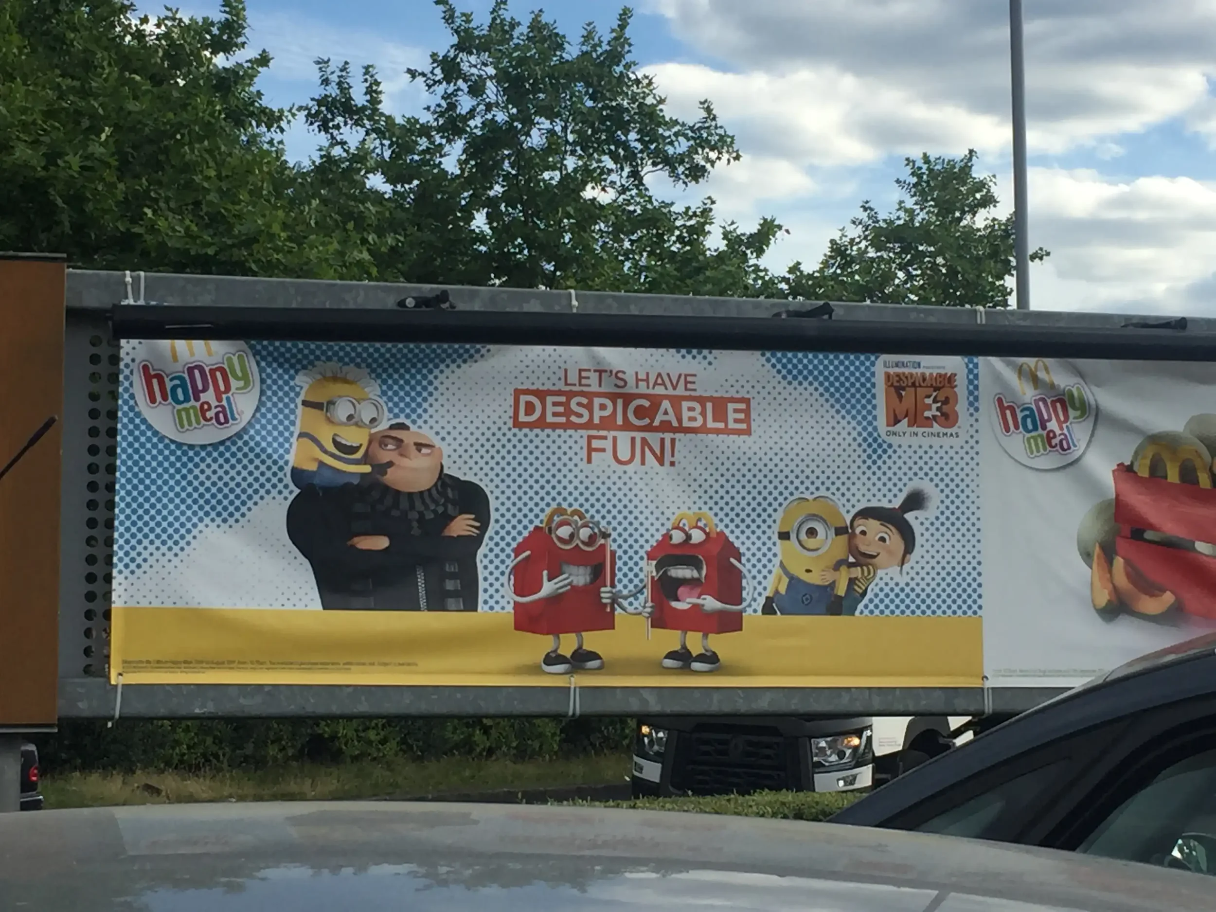 Billboard promoting the movie 'Despicable Me 3' featuring Minions and other characters with the text 'Let's have despicable fun!' and the 'Happy Meal' logo.
