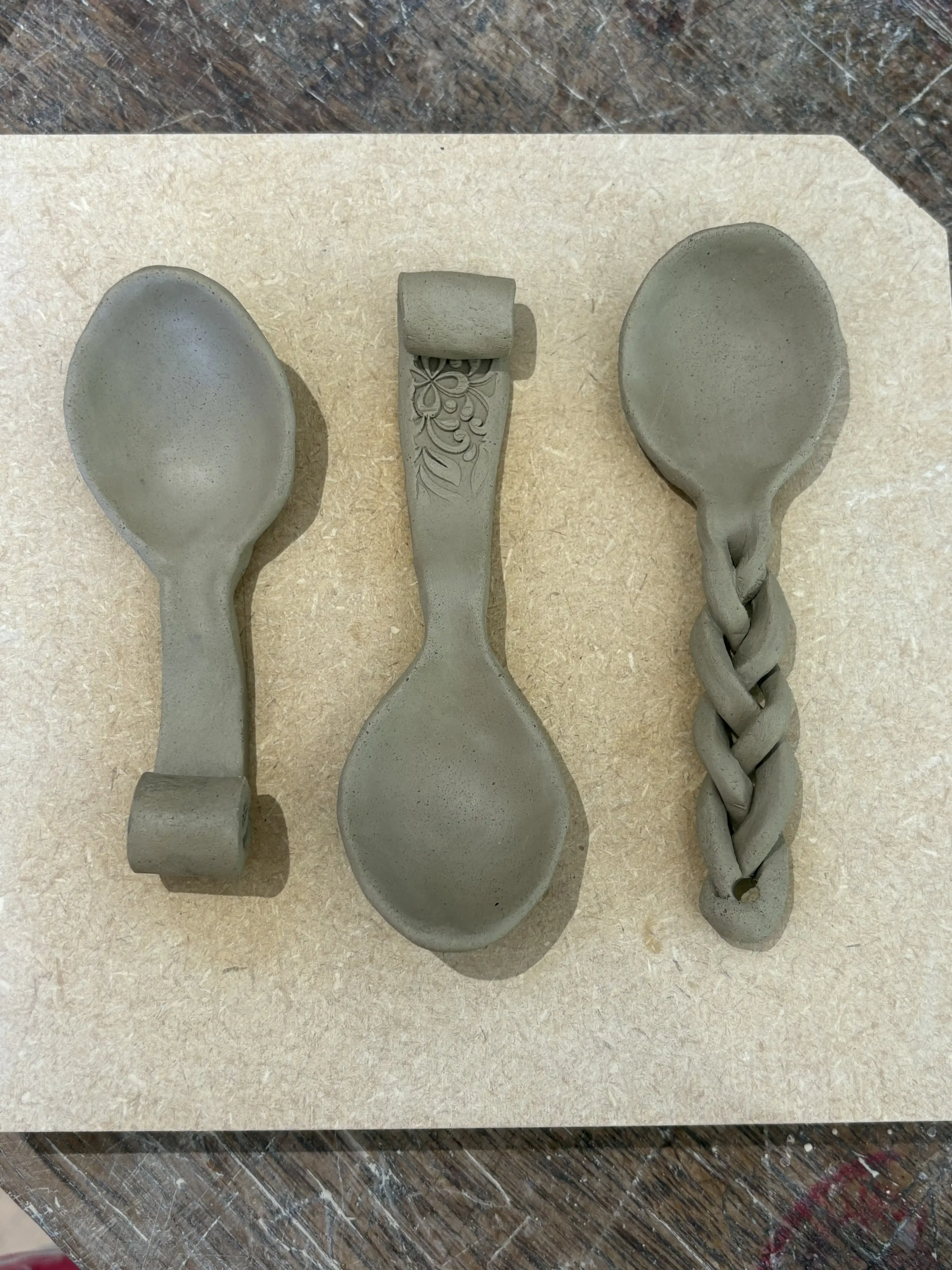 Three unglazed ceramic spoons on a light-coloured surface.