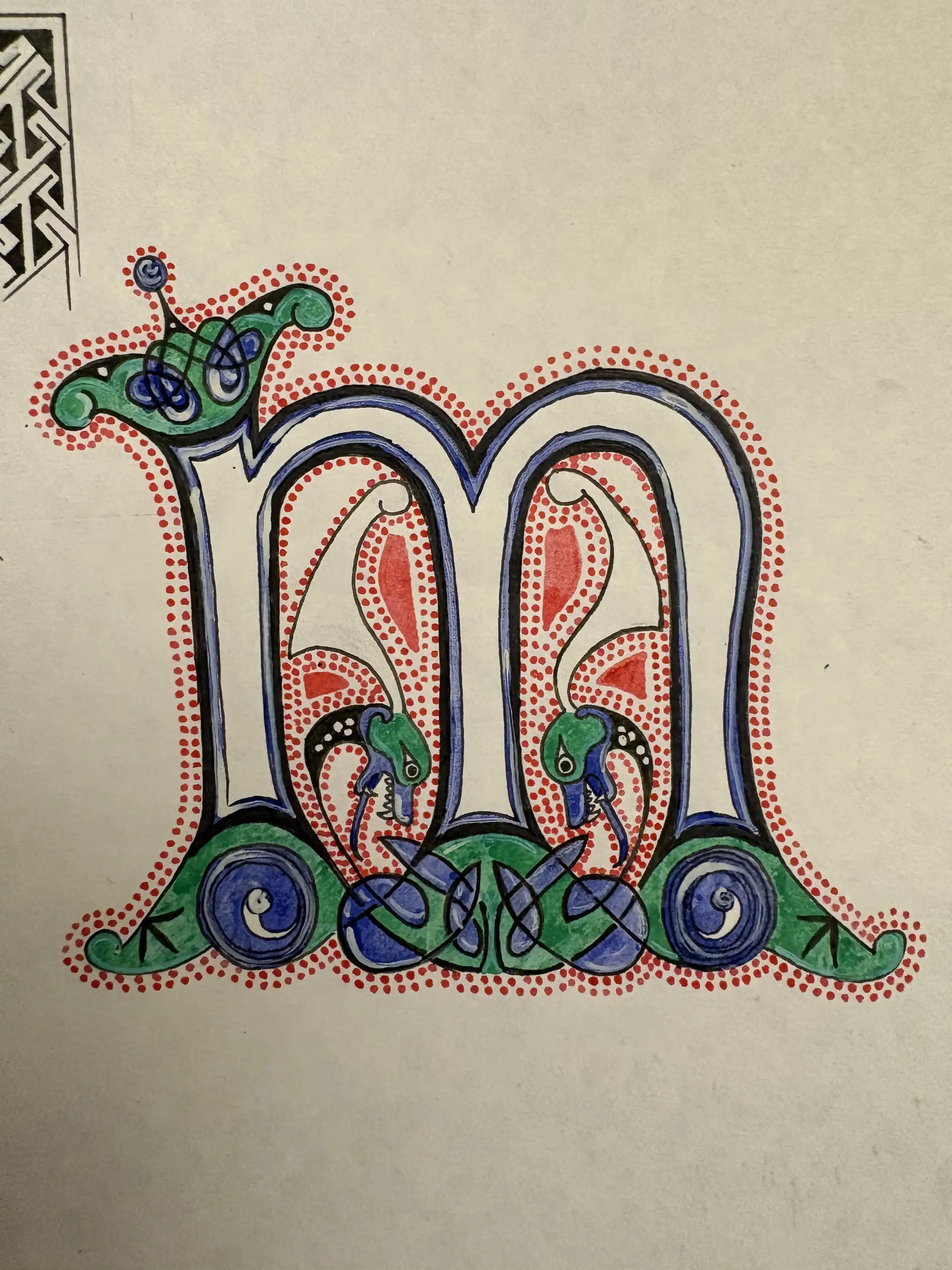 Decorative letter 'm' with intricate patterns, green, blue, and red accents, and embellishments resembling foliage and scrollwork.