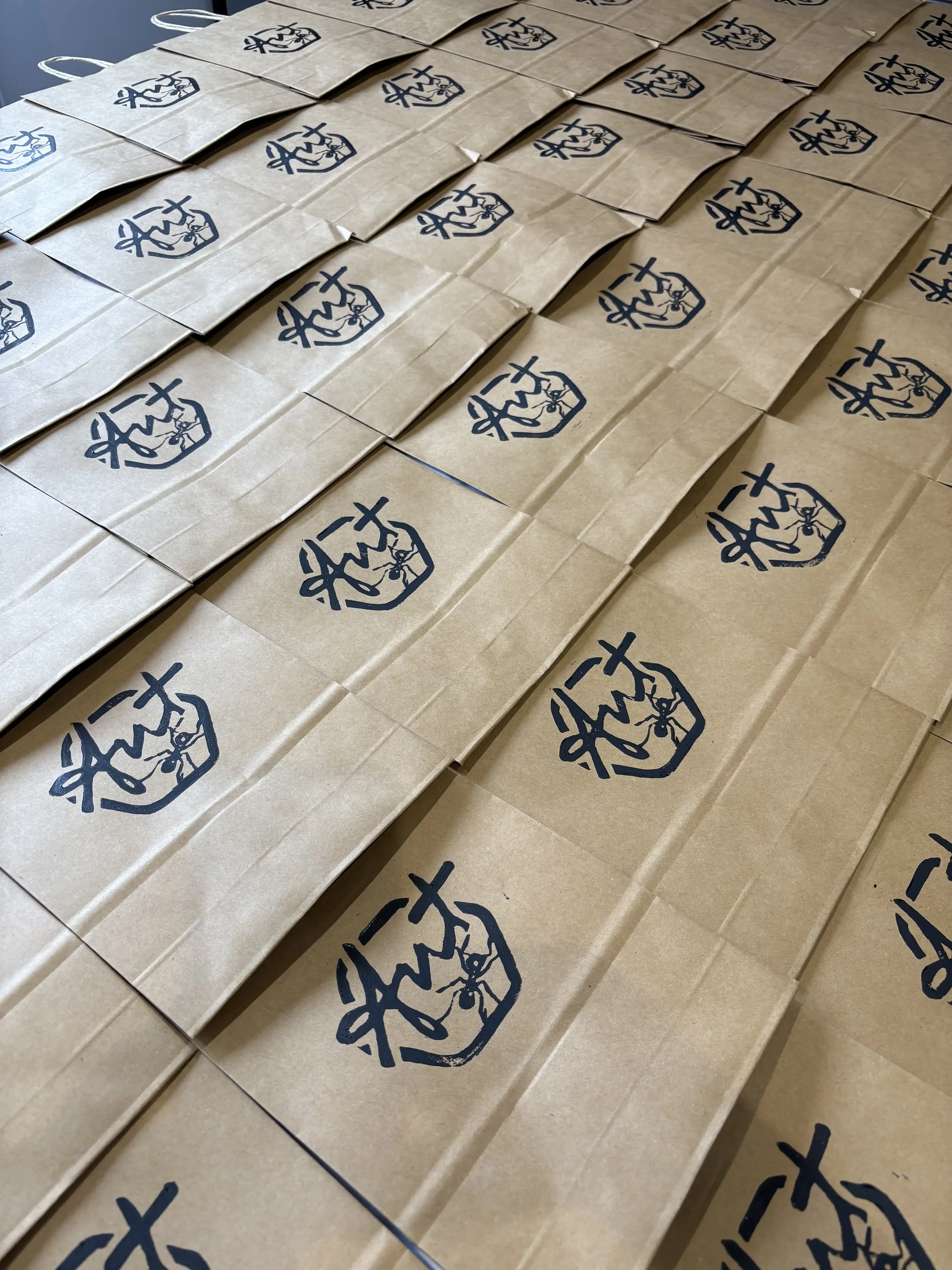 Multiple brown paper bags with blue printed logos arranged on a flat surface.