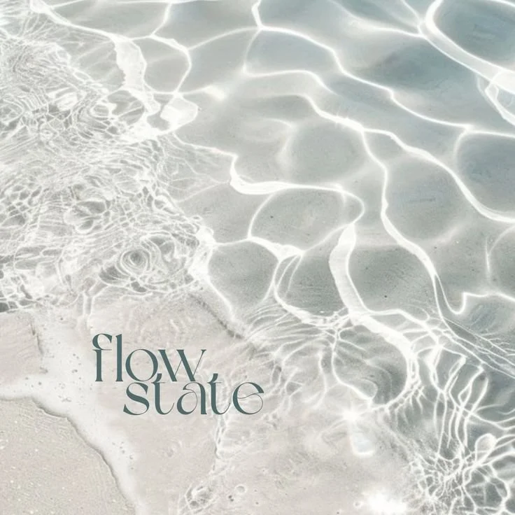 Close-up of clear ocean water with gentle waves on a sandy beach, with the words 'flow state' written in stylish font.
