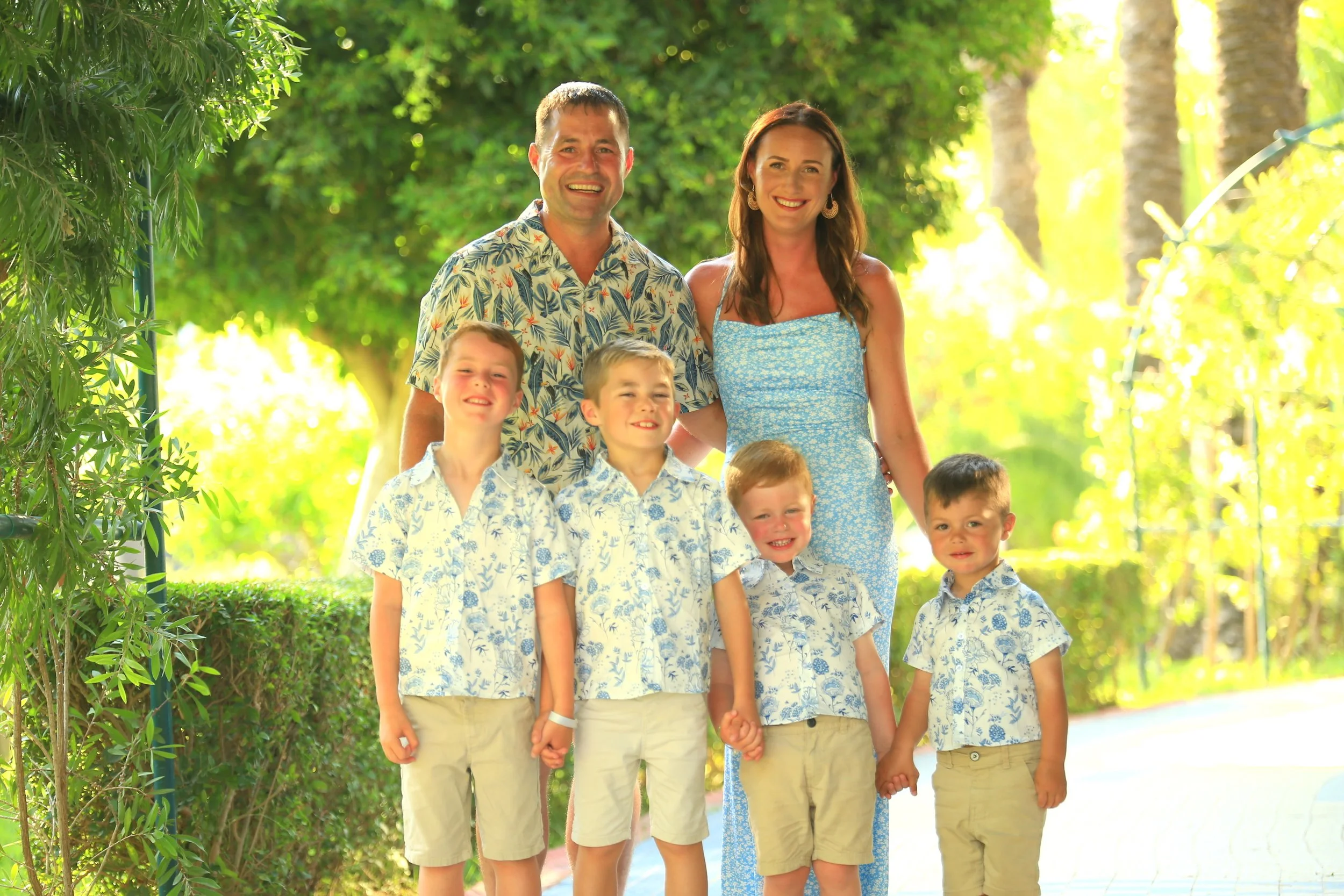 Family of six on holiday, two adults and four children enjoying a sunny, green outdoor destination.