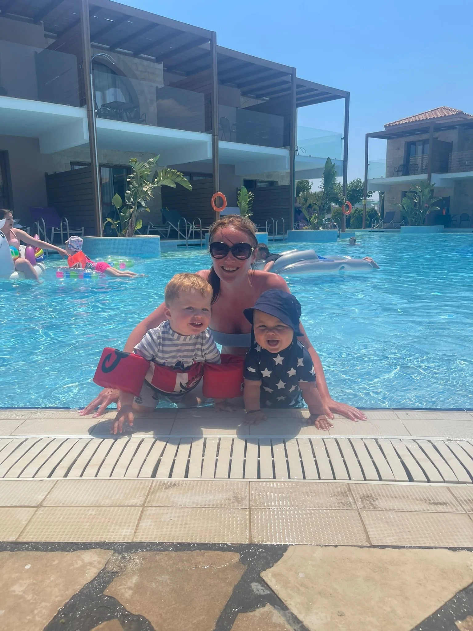 Parent with two toddlers enjoying a pool on a family vacation