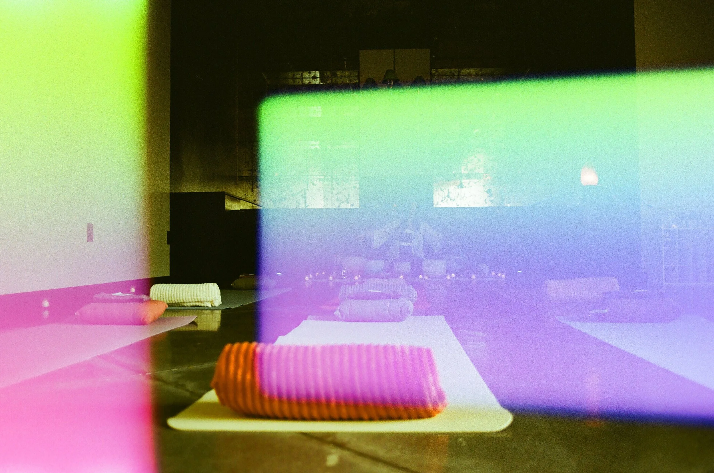Colorful light reflections over a yoga or meditation studio with mats and towels on the floor.