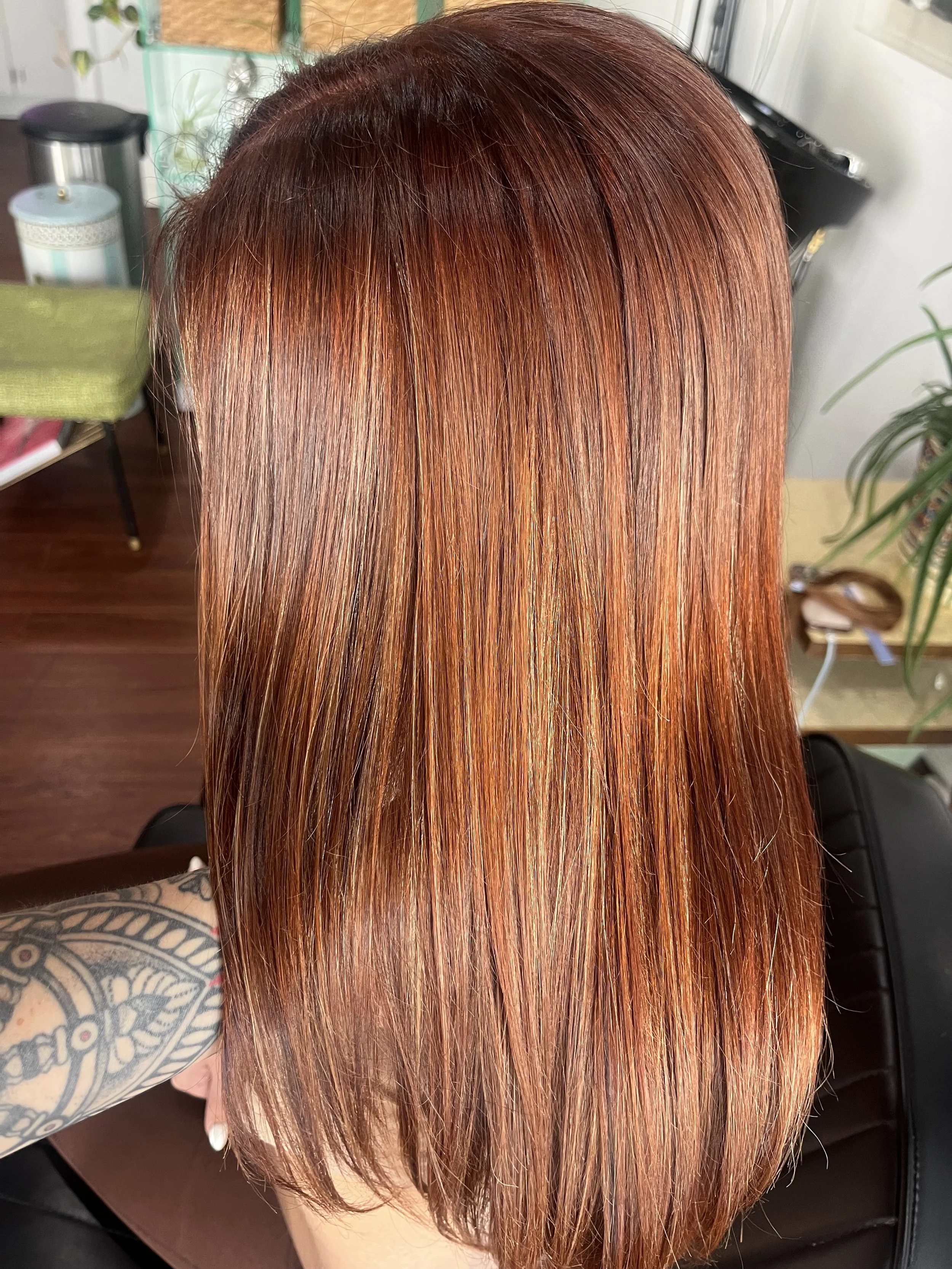 Close-up of a person's shiny, straight hair dyed a vibrant copper red color.