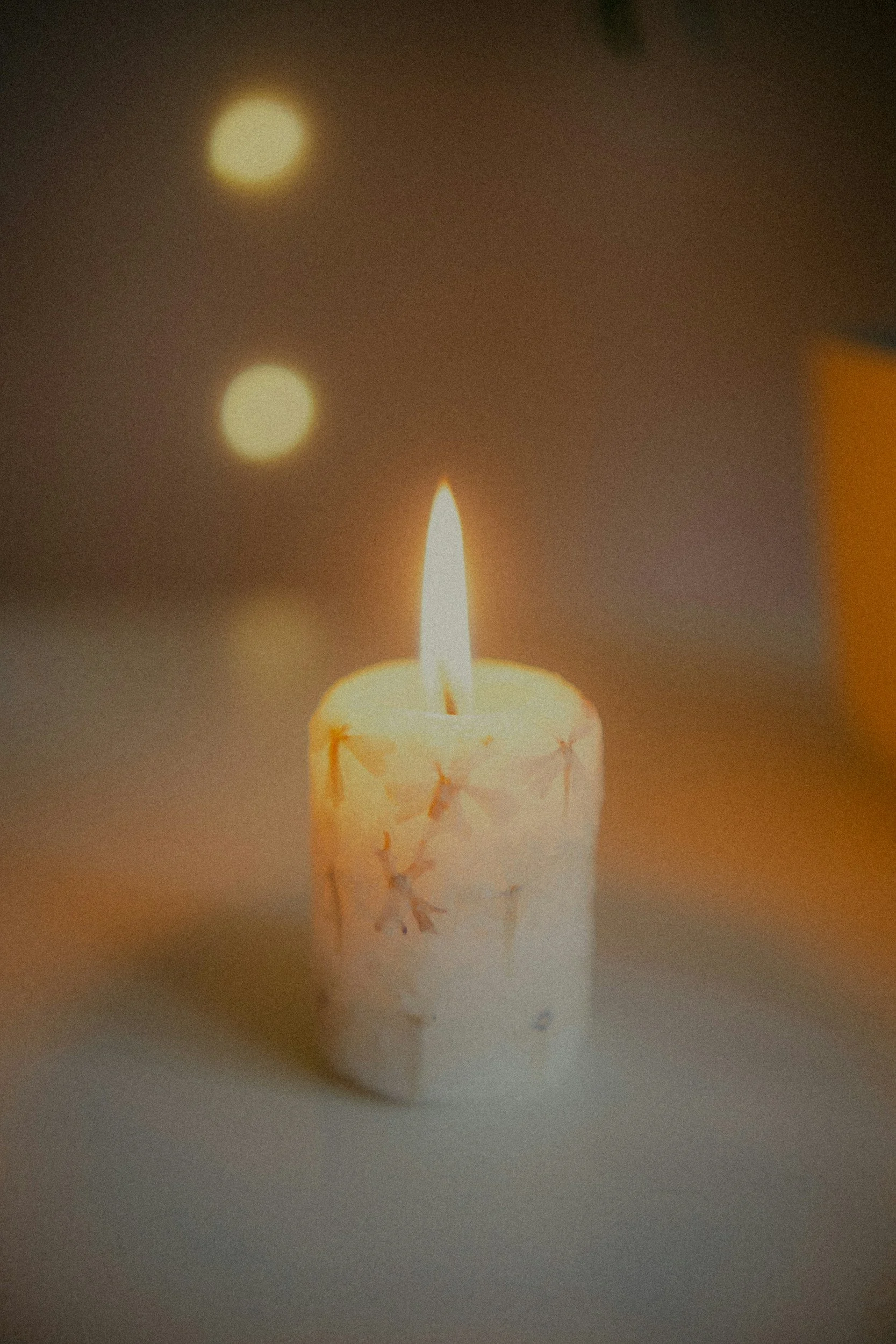 A lit birthday candle on a cake with a blurred background and warm lighting.