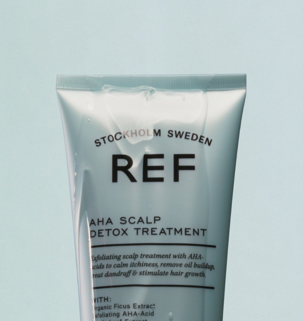 A tube of REF AHA scalp detox treatment with text indicating it’s an exfoliating scalp treatment with AHA acids from Stockholm, Sweden.