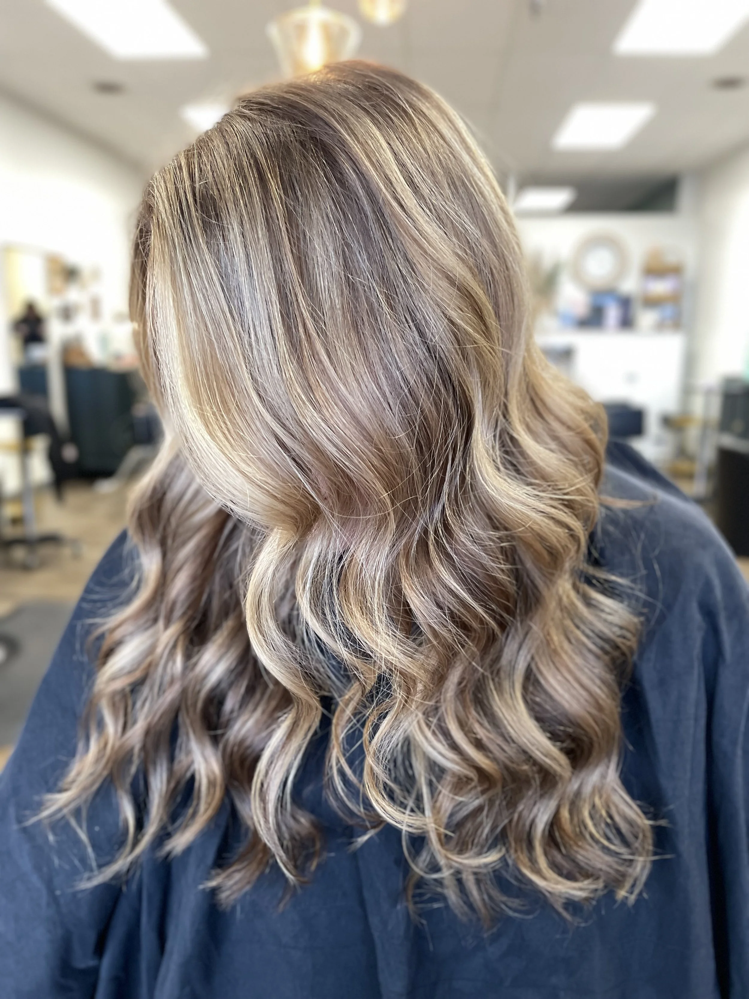 Woman with styled, wavy, blonde hair in a salon.