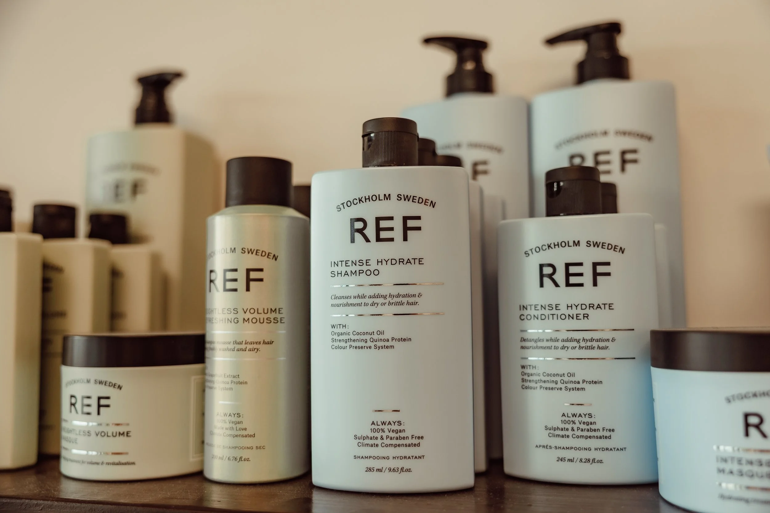 Collection of REF hair care products including shampoo, conditioner, and mousse on a shelf.