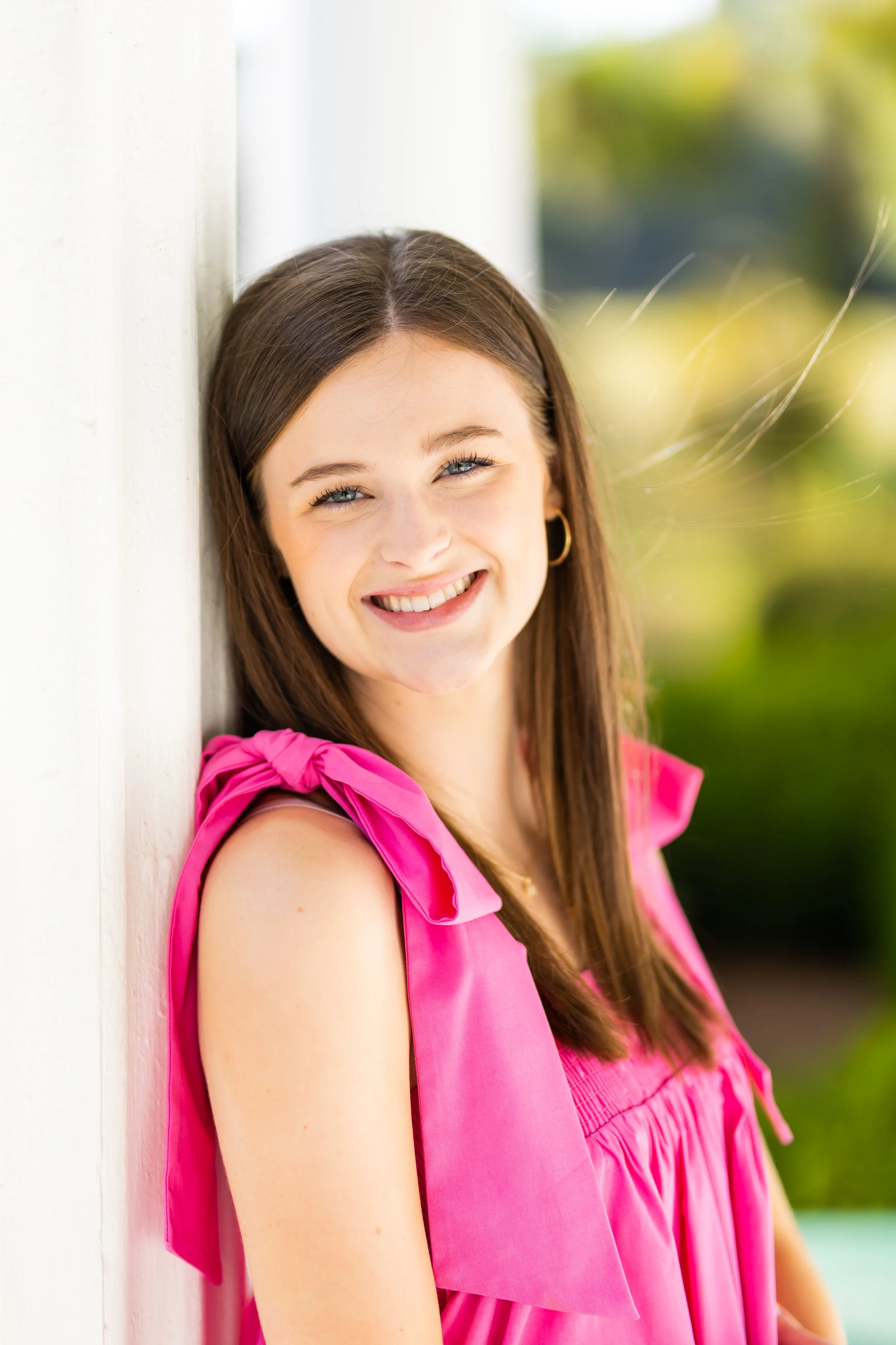 A headshot of Ruth wearing a pink top leaning against a white wall.