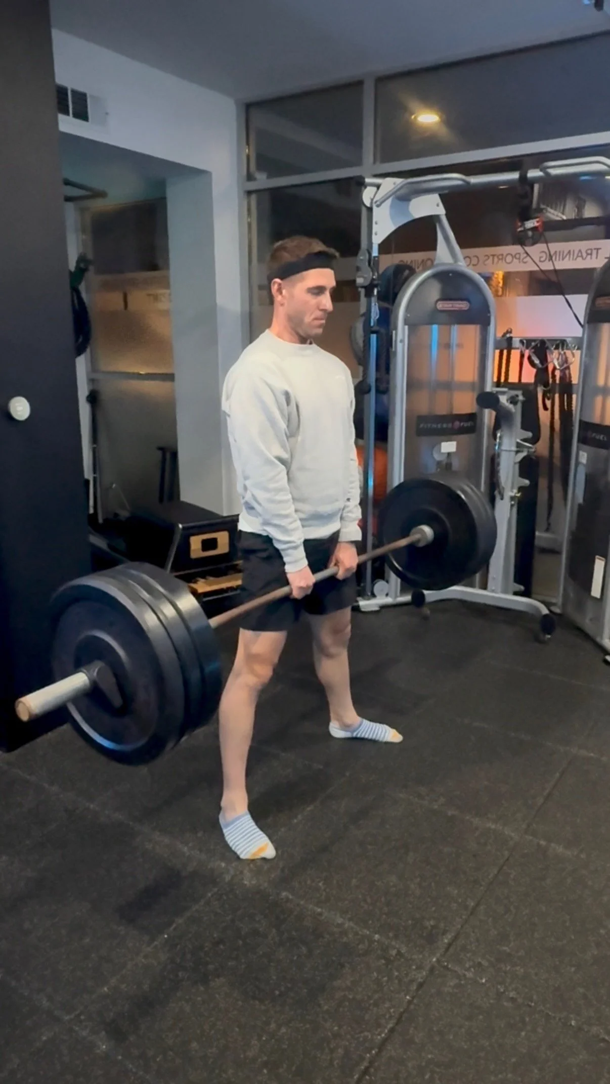 A man lifting a barbell with weights in a gym.