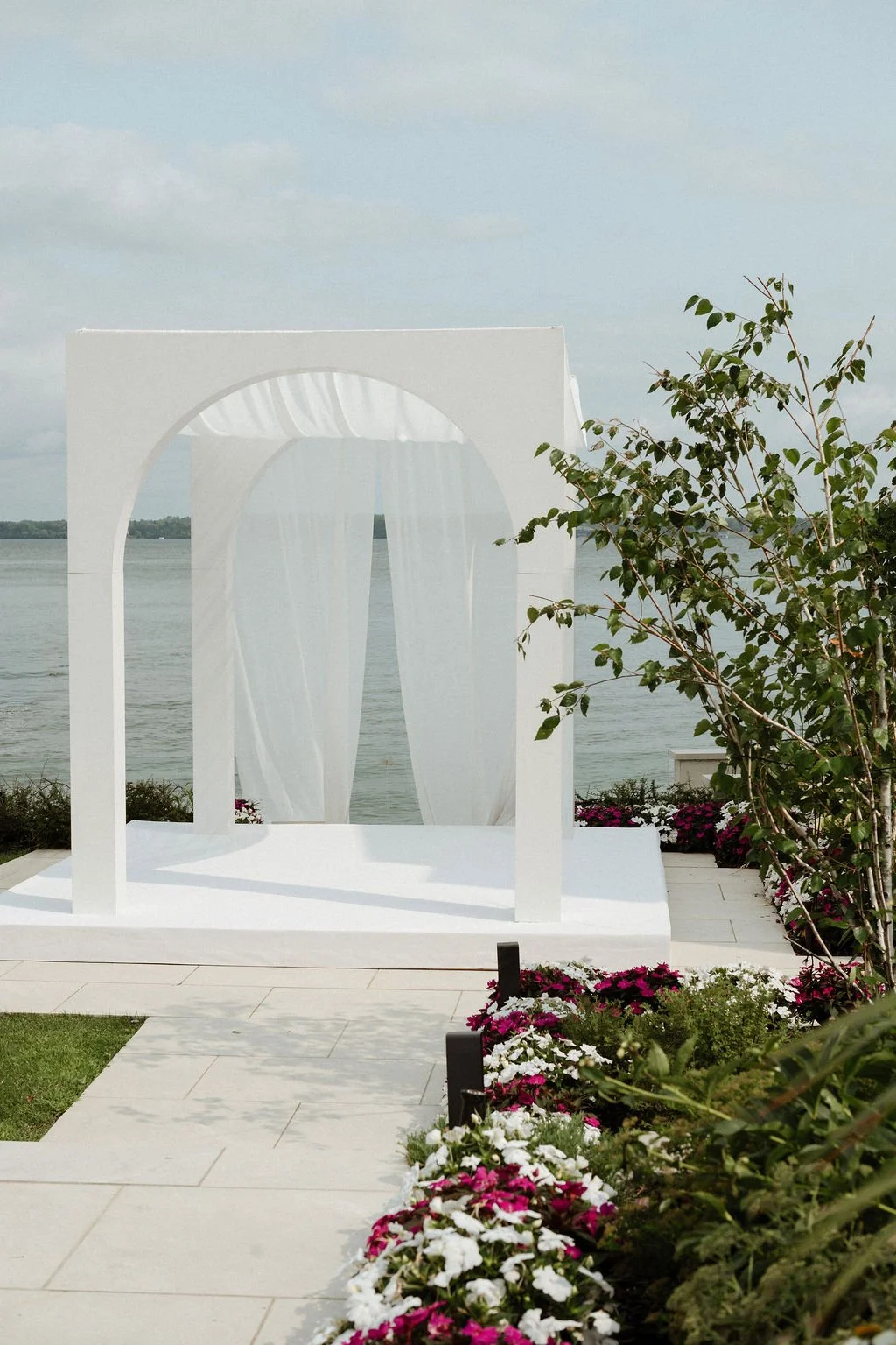 ARC white freestanding arch chuppah with integrated stage and flowing draping