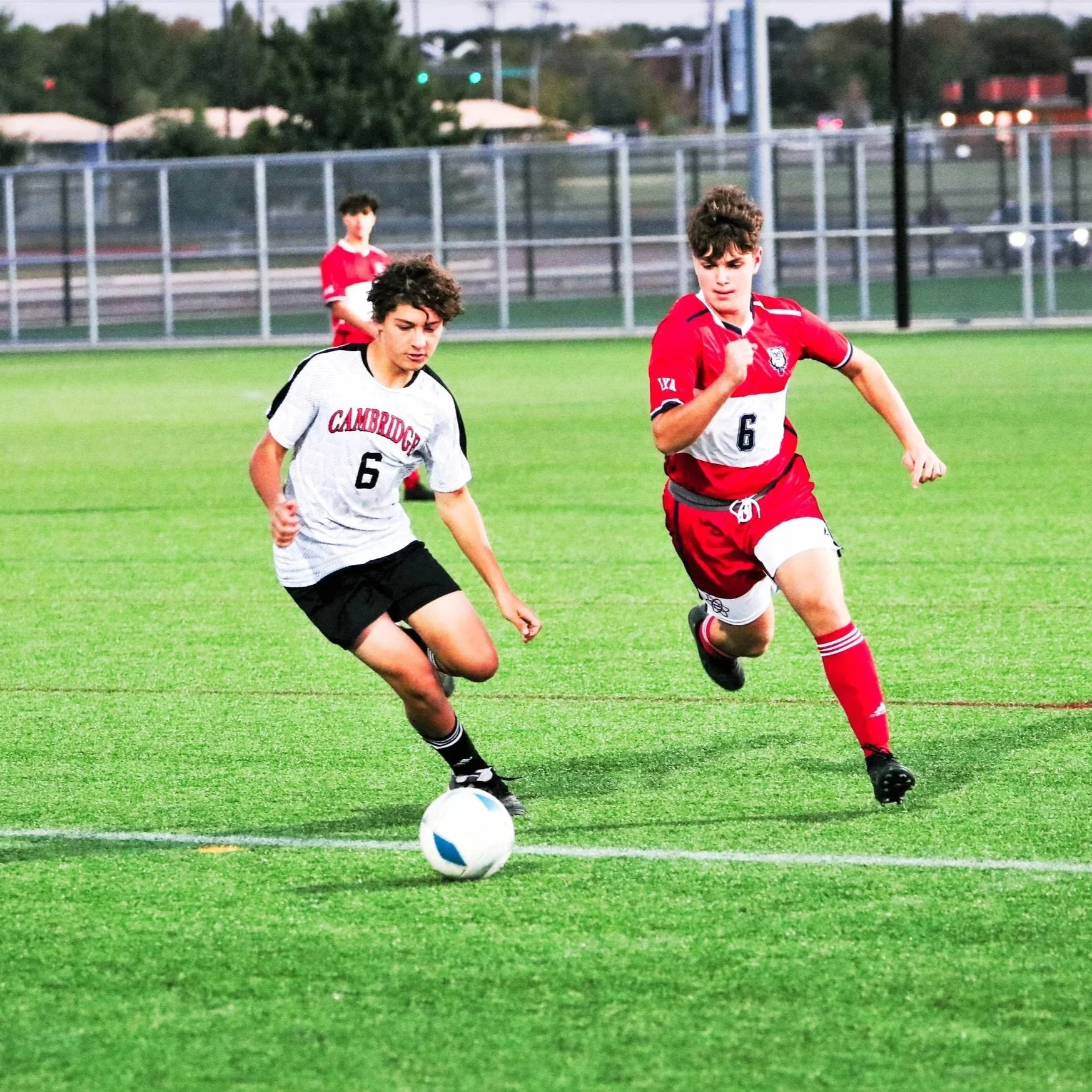 A student from the Cambridge School of Dallas varsity soccer team next to an opponent during a competitive match.
