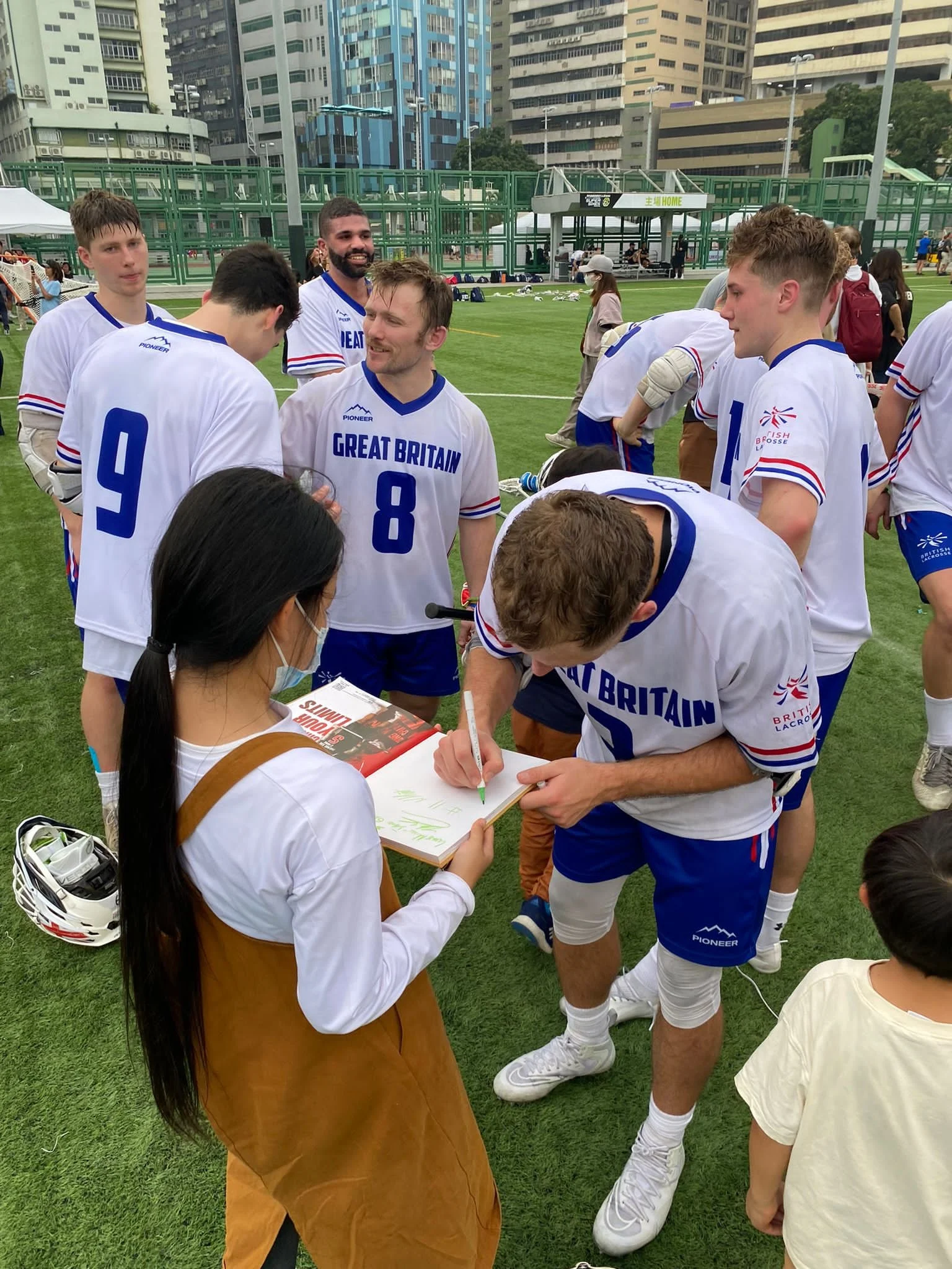 Lacrosse athletes signing autographs for young fans.