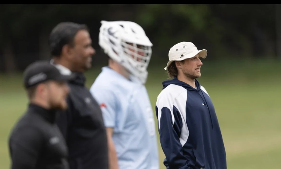 Lacrosse coach standing on a grass field during a training session in London.
