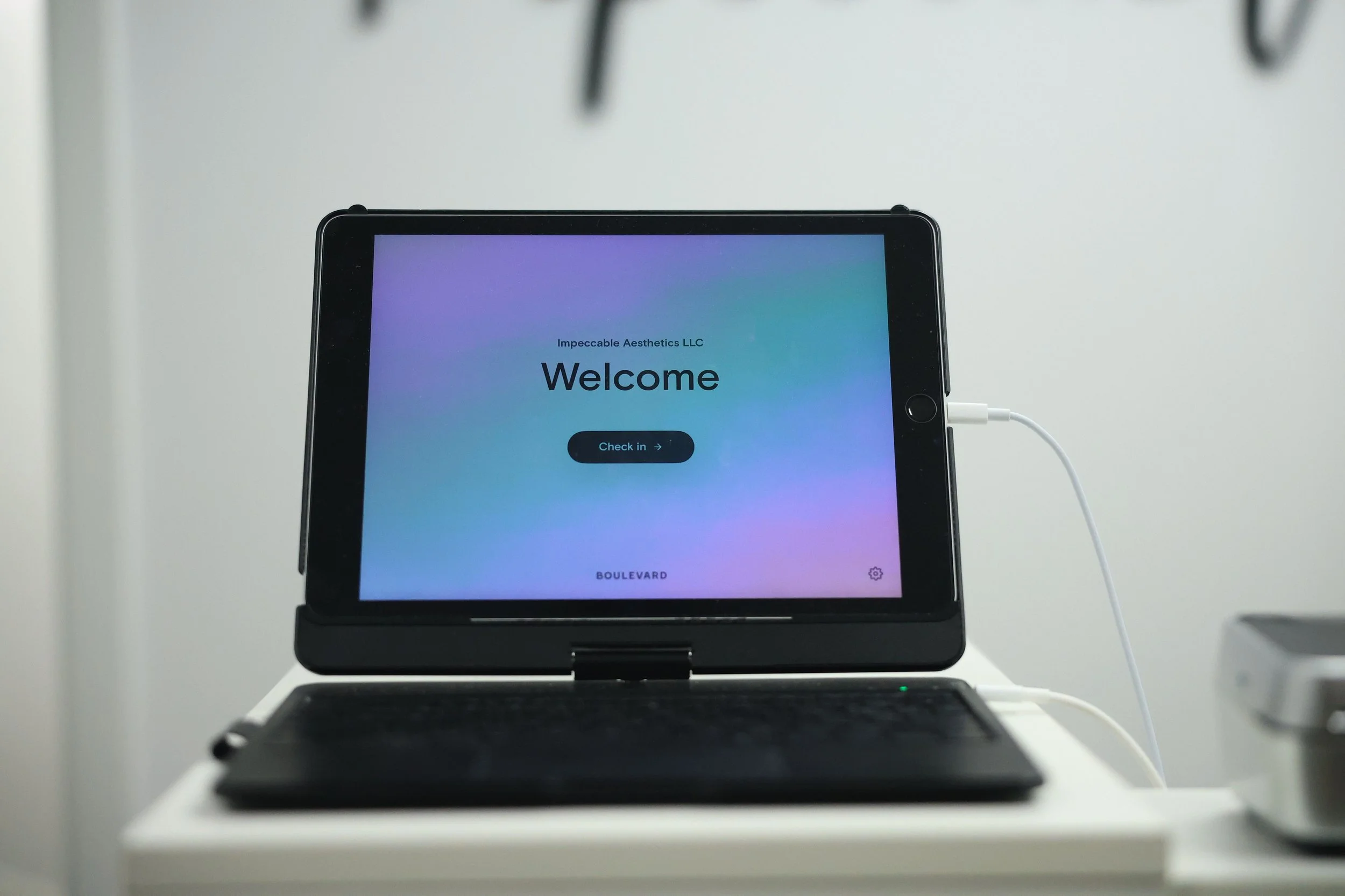 An iPad with a check-in screen for Impeccable Aesthetics medspa displayed.