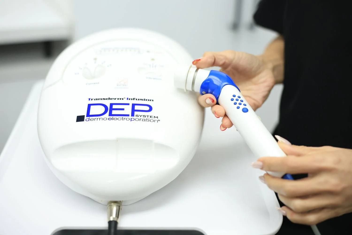 A person holding a handheld device positioned on a medical machine labeled DEP dermo electroperation for skin treatment.