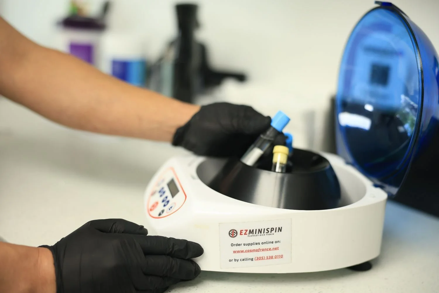 Gloved hands loading blood vials into centrifuge to prepare platelet-rich fibrin for PRF injections near me.